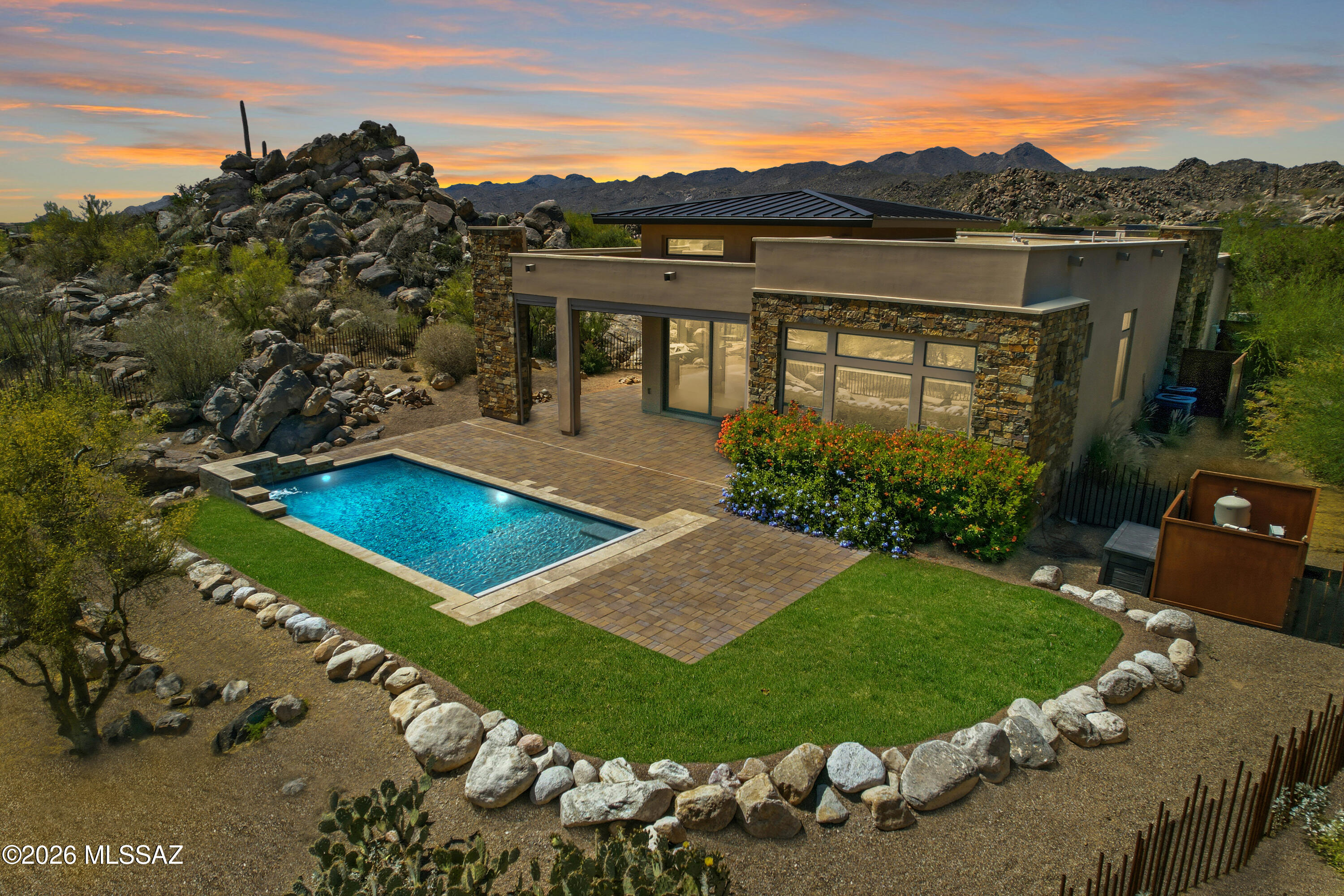 Welcome to an extraordinary opportunity in the exclusive Stone Canyon community--where luxury, privacy, and some of Southern Arizona's most spectacular views come together in perfect harmony.

Why wait years to design and build when this better-than-new masterpiece is ready to enjoy today? Meticulously crafted with premium finishes, designer fixtures, and exceptional attention to detail, every inch of this home reflects quality and sophistication.

Perched to capture breathtaking panoramic mountain and desert vistas, this residence offers a front-row seat to sunsets that seem almost unreal. As the sky transforms each evening into a stunning display of color, you'll quickly appreciate why this setting is among Stone Canyon's most captivating. The expansive primary suite serves as a private retreat, where you can wake each morning to sweeping views and unwind in a spa-inspired bath complete with an oversized custom walk-in closet. Each guest bedroom features its own private ensuite, providing comfort and privacy for family and visitors alike, while a versatile bonus room offers the flexibility of a home office, media room, fitness space, or personal retreat.

Natural light floods the open-concept great room, creating an inviting atmosphere that seamlessly blends indoor and outdoor living. Step outside to the covered patio, where power rolling shutters create a true extension of the home--perfect for year-round entertaining, relaxing by the gas fireplace, or simply taking in the remarkable scenery.

The thoughtfully designed outdoor living space centers around a beautifully appointed saltwater pool featuring a Baja shelf, waterfall feature, and power retractable cover. Whether enjoying a quiet morning overlooking the mountains or gathering with friends as the sun sets across the desert landscape, the outdoor spaces were designed to make the most of this exceptional setting.

This is more than a home--it's a lifestyle. A rare opportunity to own a move-in-ready luxury residence in one of Arizona's most coveted communities without the time, expense, and uncertainty of building new.
Experience Stone Canyon at its finest. The views, the sunsets, and the craftsmanship are simply unforgettable.