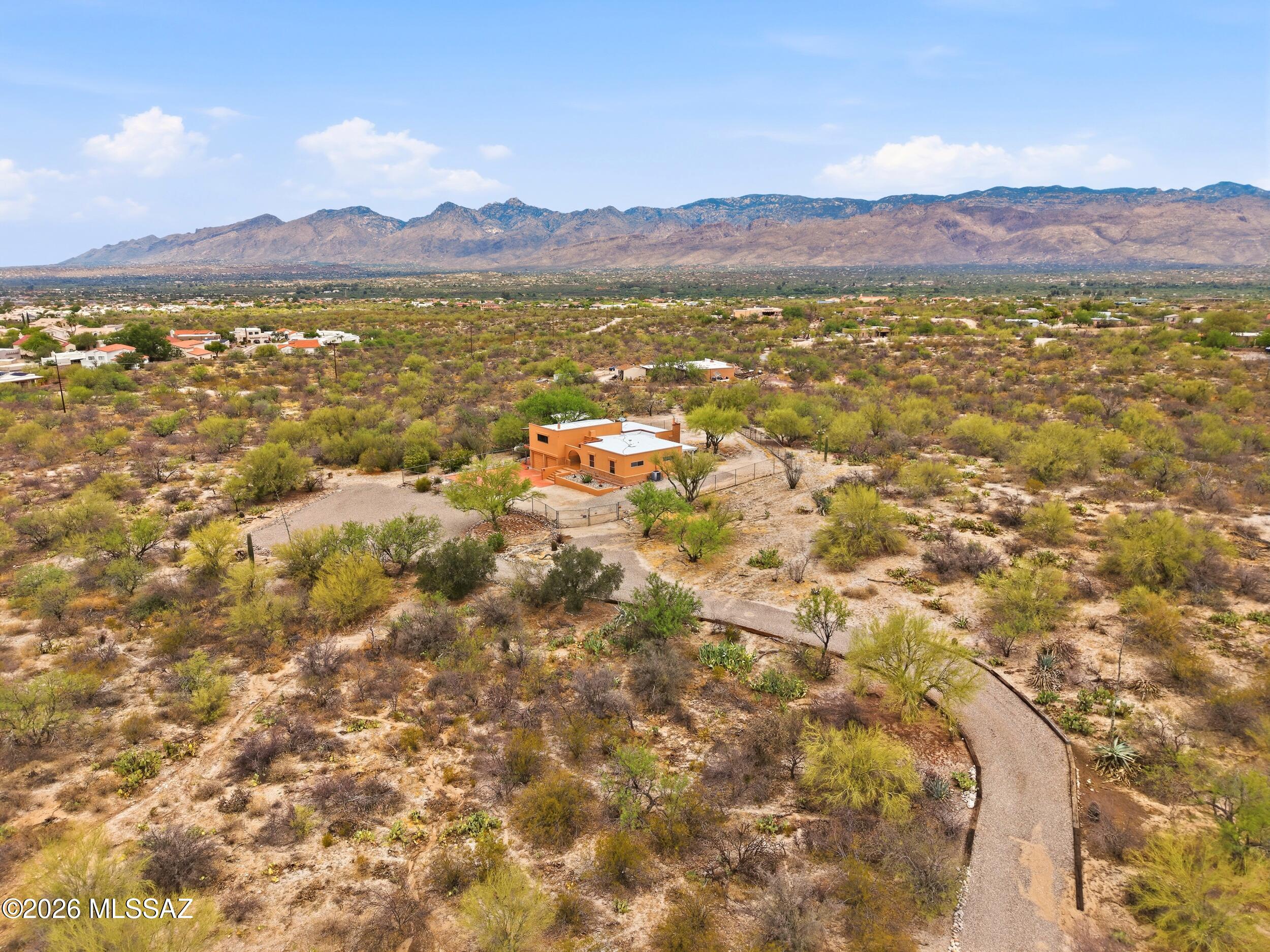 Mountain and city views set the stage for this private desert retreat on more than 4 acres in East Tucson. From sunrise over the Rincon Mountains to sparkling evening city lights, every window frames a view. The split-level home features a spacious great room with cedar-plank walls, a fireplace, and a balcony designed to capture the surrounding vistas and unforgettable Arizona sunsets. Separate guest quarters with a private entrance, kitchen, bedroom, and fireplace provide exceptional flexibility for extended guests, multi-generational living, or a private home office. A heated and cooled basement workshop, 2-car garage, and large storage shed complement a setting that is increasingly difficult to find. Experience the space, privacy, and authentic Arizona lifestyle where the Catalina Mount