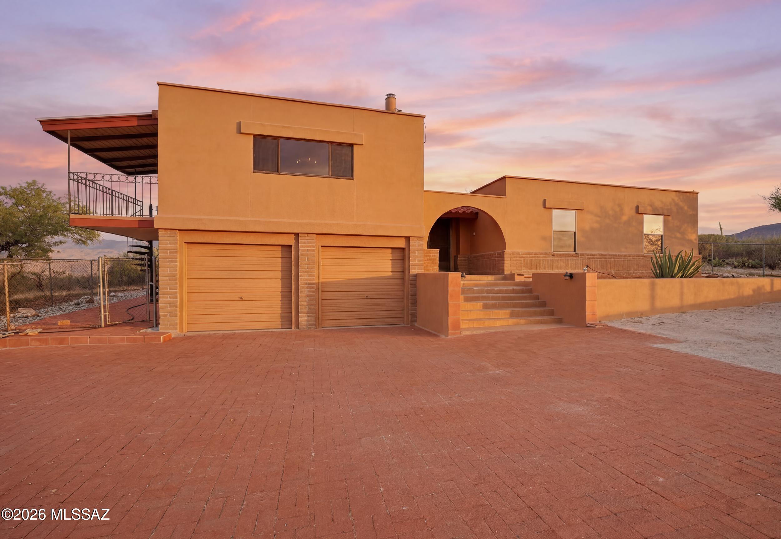 Mountain and city views set the stage for this private desert retreat on more than 4 acres in East Tucson. From sunrise over the Rincon Mountains to sparkling evening city lights, every window frames a view. The split-level home features a spacious great room with cedar-plank walls, a fireplace, and a balcony designed to capture the surrounding vistas and unforgettable Arizona sunsets. Separate guest quarters with a private entrance, kitchen, bedroom, and fireplace provide exceptional flexibility for extended guests, multi-generational living, or a private home office. A heated and cooled basement workshop, 2-car garage, and large storage shed complement a setting that is increasingly difficult to find. Experience the space, privacy, and authentic Arizona lifestyle where the Catalina Mount