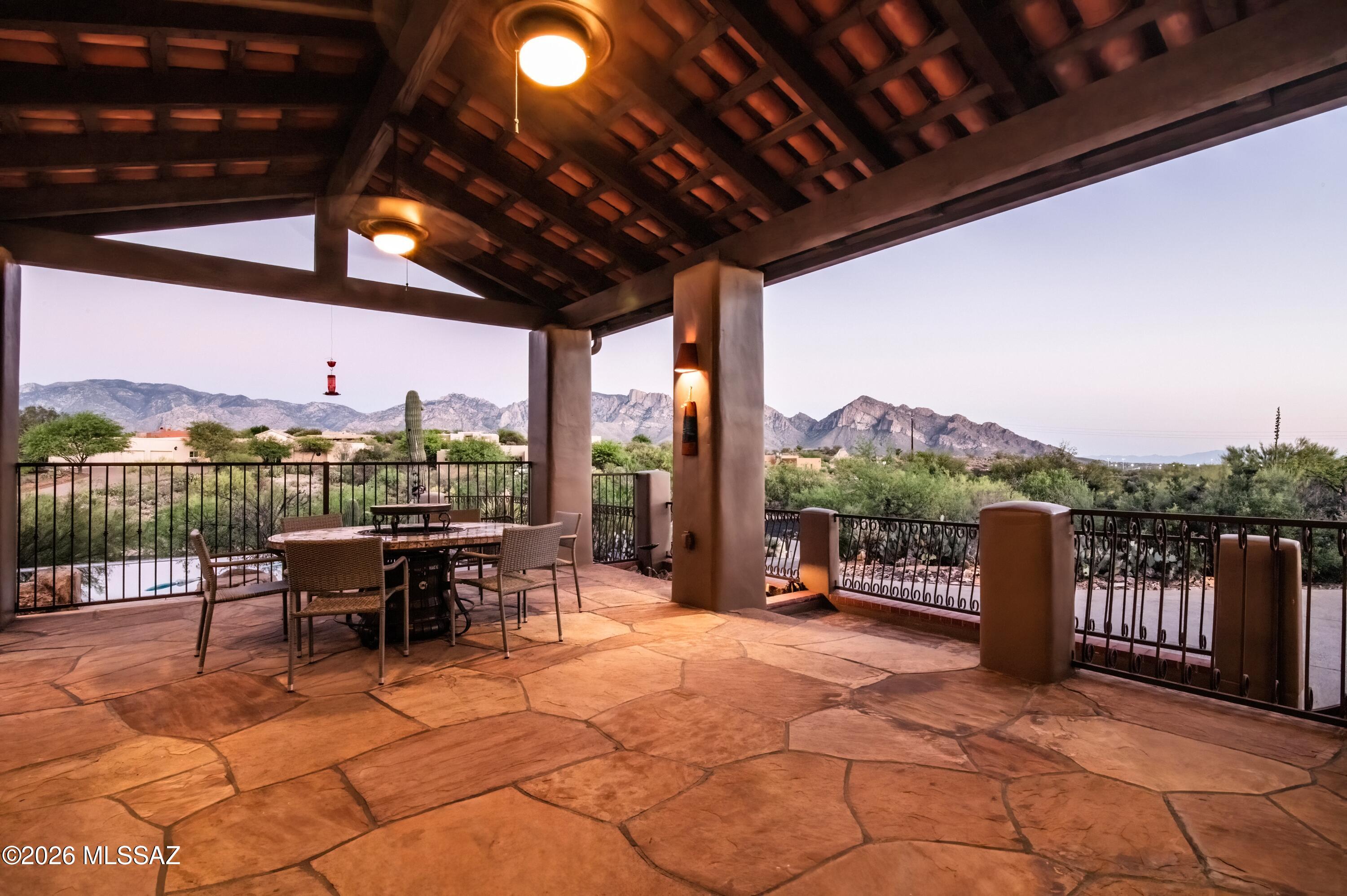 Perched high in the coveted Coyote Ridge enclave of Oro Valley, this extraordinary, gated estate captures the essence of elevated desert luxury. Privately tucked at the end of a cul-de-sac on a premier 1.2-acre ridge-top lot, the home is surrounded by sweeping, unobstructed views of the Catalina Mountains and Pusch Ridge offering a
level of serenity and privacy that is truly rare. Designed for both grand entertainment and refined everyday living, the outdoor experience is nothing short of spectacular. Multiple covered patios with rich wood beams and corbels frame expansive living spaces, while a custom-tiled built-in BBQ, outdoor shower, and a stunning negative-edge Pebble Tec pool with cascading rock waterfall and spa create a true resort-style retreat. From sun-drenched afternoons poolside to unforgettable Arizona sunsets and stargazing evenings, every moment here is elevated. Inside, the home exudes warmth and craftsmanship with wood like tile floors, solid knotty alder doors, and thoughtfully curated finishes throughout. The great room is both inviting and impressive, featuring soaring vaulted ceilings, a striking stacked-stone gas fireplace, and a dramatic wall of windows that perfectly frame the surrounding mountain vistas. The gourmet kitchen is
designed to impress, complete with stainless steel double ovens, a 5-burner gas cooktop, upgraded granite surfaces, custom cabinetry, and a seamless flow into the breakfast bar and dining area, each space thoughtfully positioned to capture
breathtaking views. The primary suite is a true retreat, offering a private sitting area with a dual-sided fireplace, direct patio access, and a spa-inspired bath featuring a jetted soaking tub, oversized tiled shower, executive-height granite vanities, and generous
walk-in closets. An adjoining flex space creates the perfect setting for a private office, fitness room, or relaxation lounge. The quality and attention to detail are evident at every turn in the home with fresh interior and exterior paint plus new plush carpet. The
home is both timeless and impeccably maintained. Backing to expansive preserved open space and offering unmatched privacy, breathtaking views, and exceptional craftsmanship this is a rare opportunity to own one of Oro Valley's most distinctive
luxury properties.