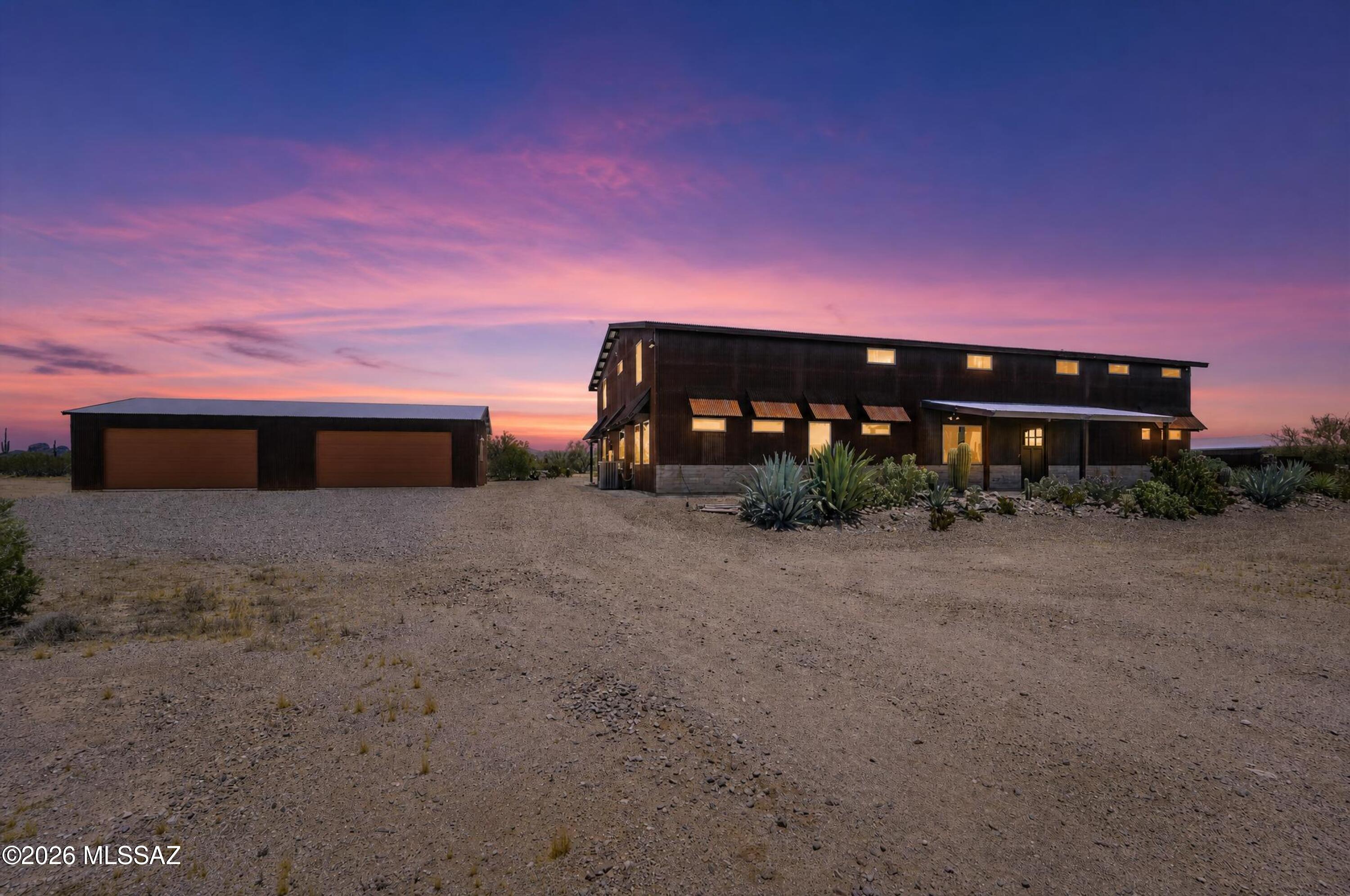 Experience Arizona desert living at its finest in this stunning luxury barndominium on 6+ private acres in desirable Marana. Built in 2020 with no HOA, this one-of-a-kind property offers 5,280 sq. ft. of versatile living space ideal for multi-generational living, a home business, guest quarters, or caregiver accommodations. Rustic charm blends seamlessly with modern comfort throughout. Enjoy a low-maintenance exterior, natural Sonoran Desert landscaping, a spacious 4-car garage, exterior storage units, and a unique 200 sq. ft. air-conditioned pet quarters with fenced outdoor run. Privacy, wide-open spaces, and endless possibilities await.