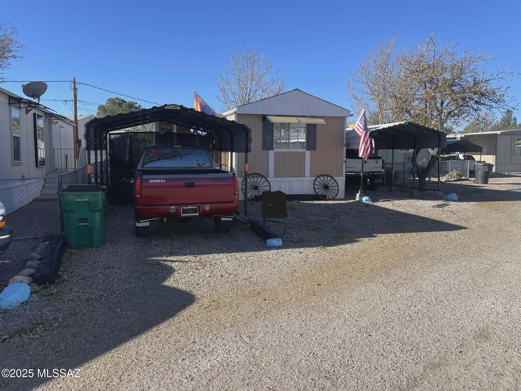 This well-maintained 2-bedroom, 1.5-bath manufactured home is located in a quiet 55+ park on leased land, with lot rent at just $400/month, including water sewer and trash also includes 6 months of prepaid lot rent and a transferrable home warranty. The home features a spacious screened-in Arizona room, perfect for relaxing or entertaining year-round. Enjoy outdoor living with a full outdoor kitchen, new gutters, and security lighting for added peace of mind. With three carports and space to park up to four vehicles, there's room for all your guests. The beautifully landscaped yard showcases native cacti and large shade trees, creating a low-maintenance desert oasis. A convenient shed provides extra storage. Ideally situated close to shopping and other local amenities.