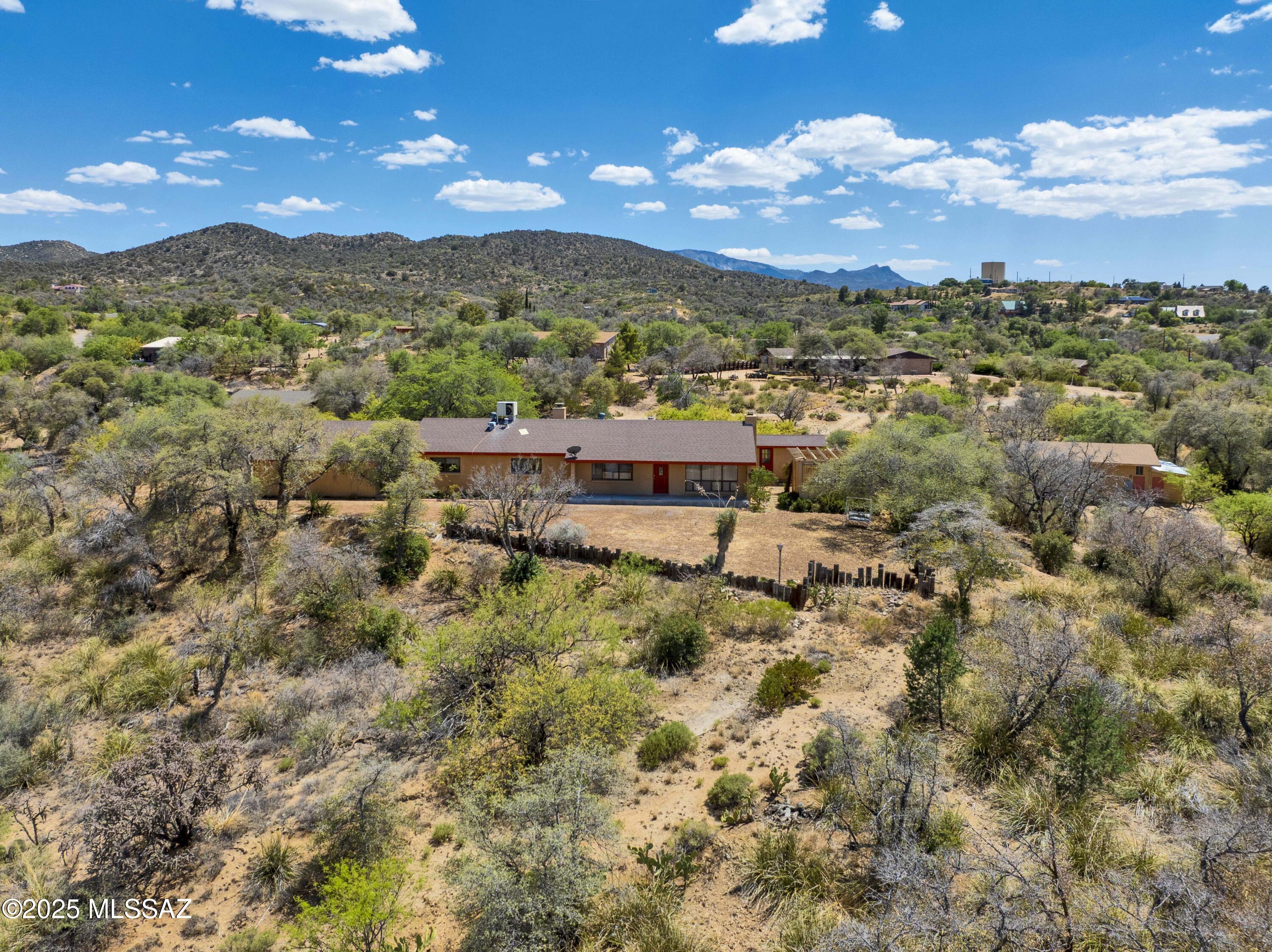 Charming Hilltop Retreat with Great Views and a Guest House on 2.58 Private Acres.  Spacious 3-bedroom, 3-bath home, 1,893 sq ft of living space in the home and 1263 in the guest house nestled a top a serene hilltop. The property is beautifully covered with mature oak trees, offering shade, privacy, and a picturesque natural setting.  2 wood-burning fireplaces, with 1 located in the dining area and the 2nd one in the versatile family room/den—perfect for a potential 4th primary suite with its own bathroom, creating a desirable split floor plan layout. Large dining area with a rock fireplace, a sunroom/Arizona room, and a pantry with ample storage. Enjoy outdoor living on the expansive brick patio, ideal for entertaining or relaxing under the trees. 2-car carport with 2 storage room laundry room with extra storage. Hot tub (conveys as-is; owner has never used it) The property also includes a charming guest home approximately 1,263 square feet complete with a covered front porch, AC, large storage room, bathroom, and kitchenette area perfect for guests, multi-generational living, artist studio or work shop. This unique property combines space to spread out, privacy, and versatility ideal for those seeking comfort and room to grow in a peaceful, oak-studded setting.