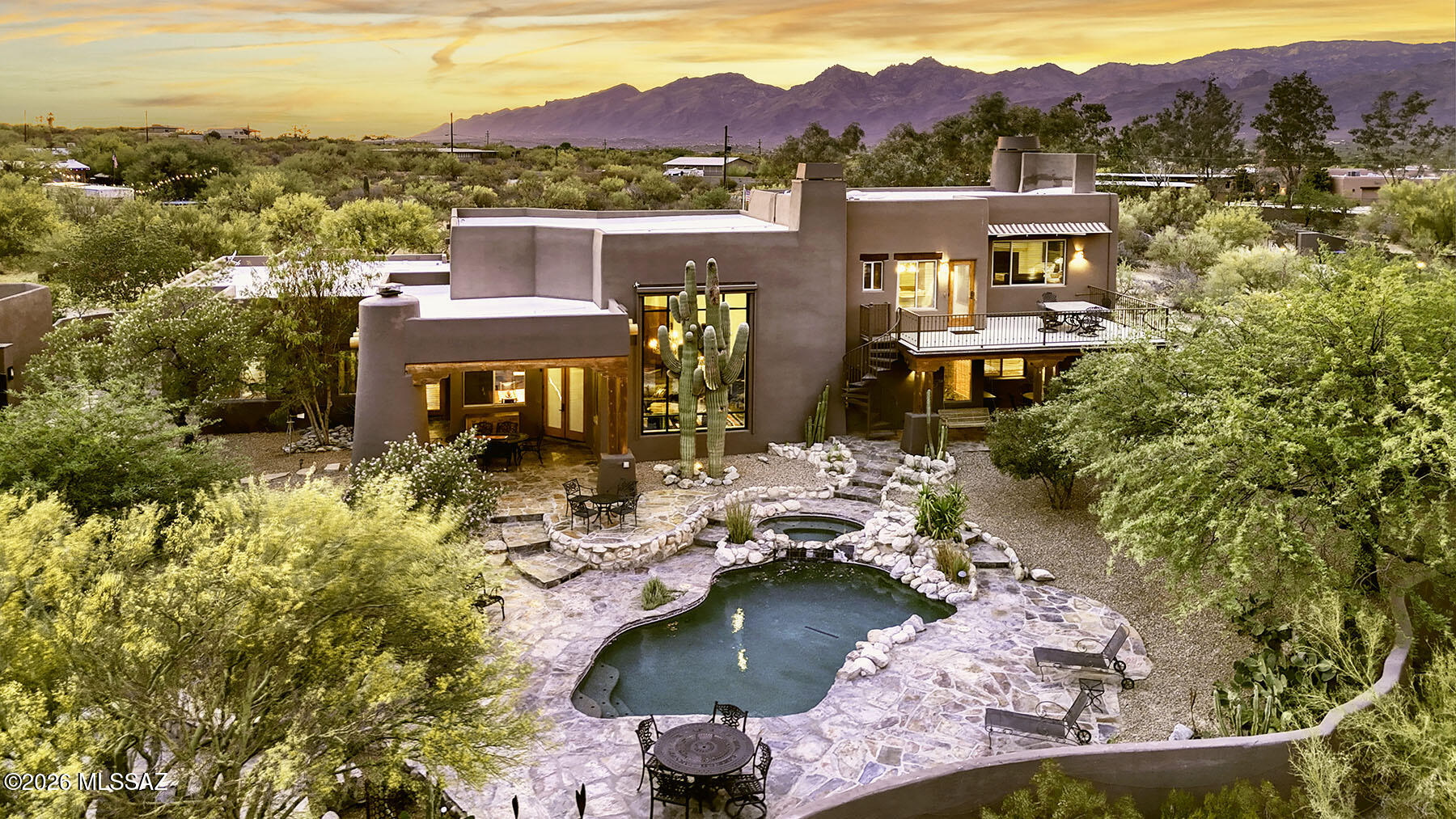 Nestled behind custom gates on over five private acres, this extraordinary equestrian estate is surrounded by sweeping mountain views and the natural beauty of the Sonoran Desert. A long, illuminated driveway welcomes you to a stunning custom Southwest residence and authentic hacienda-style casita, thoughtfully designed to blend luxury living with timeless desert charm. Equestrians will appreciate the exceptional setup featuring a 5-stall barn with tack room, two riding arenas, and convenient access to the scenic trails of Saguaro National Park East. Inside, the dramatic great room showcases soaring 24-foot ceilings, rich flooring, exposed beams, a striking slate fireplace, and walls of glass framing spectacular saguaros and mountain views. The updated chef's kitchen is truly the heart of the home featuring granite counters, hand-rubbed maple cabinetry, large center island, 6-burner cooktop, double ovens, Dacor warming drawer, walk-in pantry, casual dining, and bar seating. The luxurious main-level Primary Suite offers its own fireplace, cozy window seat, spa-inspired remodeled bath with standalone soaking tub wrapped in stacked stone, dual granite vanities, designer shower, concrete flooring, two walk-in closets, and private access to the patio and hot tub. The main level also includes additional bedrooms, laundry room, and oversized 3-car garage with newly coated flooring. Upstairs, a private guest retreat which is perfect for multi-generational living features a separate living area, bedroom, bath with teak wood flooring, and dining room that opens to a balcony perfectly positioned for stunning mountain views and moonrises. Outdoor living is equally impressive with a covered patio featuring wood plank ceilings, fireplace, outdoor kitchen and BBQ area, resort-style pool and spa, and expansive yard spaces. Equestrian amenities include a fully functioning 5-stall barn with tack room, two arenas, covered RV parking, hay barn, separate exercise room, and a 700-square-foot workshop with full bath. The detached hacienda-style casita offers incredible privacy for guests with authentic architectural touches, including a welcoming wood door imported from India, and its own private yard. This home is truly an exceptional desert sanctuary offering luxury living, privacy, and premier equestrian facilities in an unforgettable setting. Adjoining 4.21 acres to the east is available for sale.
