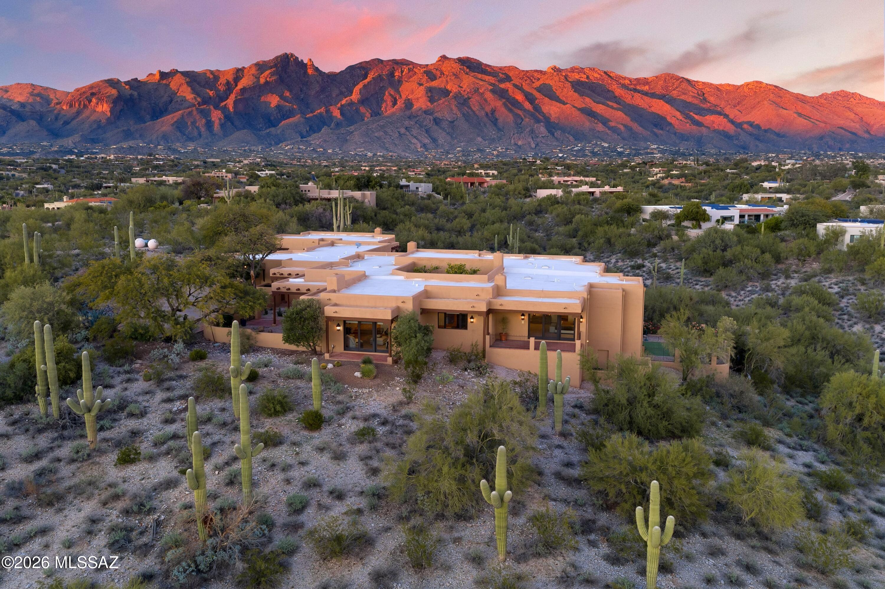 Offered for the first time in more than 20 years, this masonry/Stucco Pueblo Revival Style Estate presents a rare opportunity within District 16 Schools. Blending timeless architecture w/estate-scale living, the hilltop property spans 3.78 acres & 8,218 square feet of living space, including a private guest house. In total, the Property offers 7 bedrooms, 10 bathrooms (2 half baths), 6 fireplaces, a four-car garage, and a motor court area w/guest parking. Privately set on a 3.78 acre hilltop lot bordering a natural arroyo, the home is hidden from street view & captures sweeping 360° vistas—from Finger Rock and the Catalina Mountains to the Rincons, A-Mountain, and Tucson's city lights. Enter the main residence through an enclosed front courtyard w/views of the city & mountains all aroun The main house features five bedrooms, six full/two half baths and a lower-level bonus space perfect for a game/crafts room or use as an additional guest or kids retreat.  The guest house offers two bedrooms, two full baths, a full kitchen, fireplace, and covered patiosideal for extended family or multi-generational living. 

This home is designed to celebrate indoor-outdoor living and offers seven covered patios and multiple walled yards, a PebbleTec pool, putting green, citrus trees, rose garden, a built in BBQ & fireplacespaces equally suited for quiet mornings or unforgettable gatherings. 

Built by award-winning builder Mike Wachs and located within La Puerta, a gated enclave of just nine homes, the residence is centered around a dramatic open-sky courtyard with fountain, fireplace, and lemon trees which evoke communal gathering. Surrounding living spaces flow effortlessly, while a separate living rooms frame sunset and city views. 

The chef's kitchen anchors the home with a professional eight-burner gas range, walk-in pantry, dual sinks and dishwashers, and a warm breakfast nook with raised bee hive fireplace. The primary suite is a true retreat, featuring a fireplace, covered patio, sweeping views, and a spa-inspired bath with Talavera-tiled shower. dual dressing rooms & closets. 

Throughout this home, exceptional details including hand-hewn Viga beams, corbel arches, red oak hardwood floors, Saltillo and Talavera tile, and illuminated art nichescreate a residence that feels both grounded in history and designed for an exceptional lifestyle.