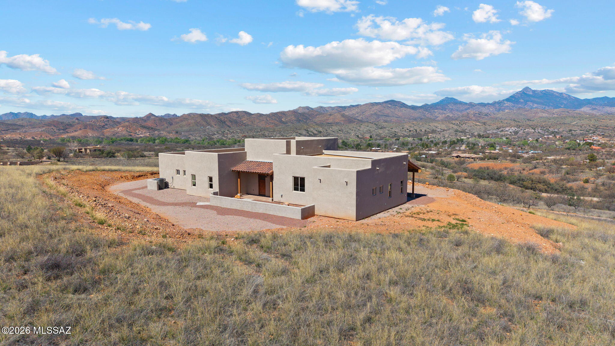 Perched high on a hillside with jaw-dropping panoramic mountain and sunset views, this stunning brand-new Southwestern-style home is nestled within The Mesa, Patagonia's prestigious gated community of fine homes just outside of town limits. Thoughtfully designed with soaring high ceilings and expansive windows that frame the breathtaking scenery, the open great room flows seamlessly into a beautifully appointed kitchen featuring granite countertops, a center island, walk-in pantry, stainless appliances, and ample dining space with sliding door access to a covered patio -perfect for taking in those golden hour views. The split floor plan offers two generous bedrooms alongside a versatile third bedroom, den, or home office, while the primary suite boasts a granite double vanity and spa-style shower. A private courtyard welcomes you at the entrance, and the home is solidly built with superior insulation (R-38 ceiling, R-19 walls) for year-round comfort and efficiency. Additional highlights include ceramic tile and laminate flooring throughout, a spacious two-car attached garage with storage, dual cooling systems, energy-efficient lighting, wide doorways and hallways, and a builder warranty for added peace of mind. Sitting on over 3.6 acres with walking trails, a paved road, and HOA-maintained common areas, this is a rare opportunity to own a move-in ready mountain retreat in one of Southern Arizona's most beloved small towns.