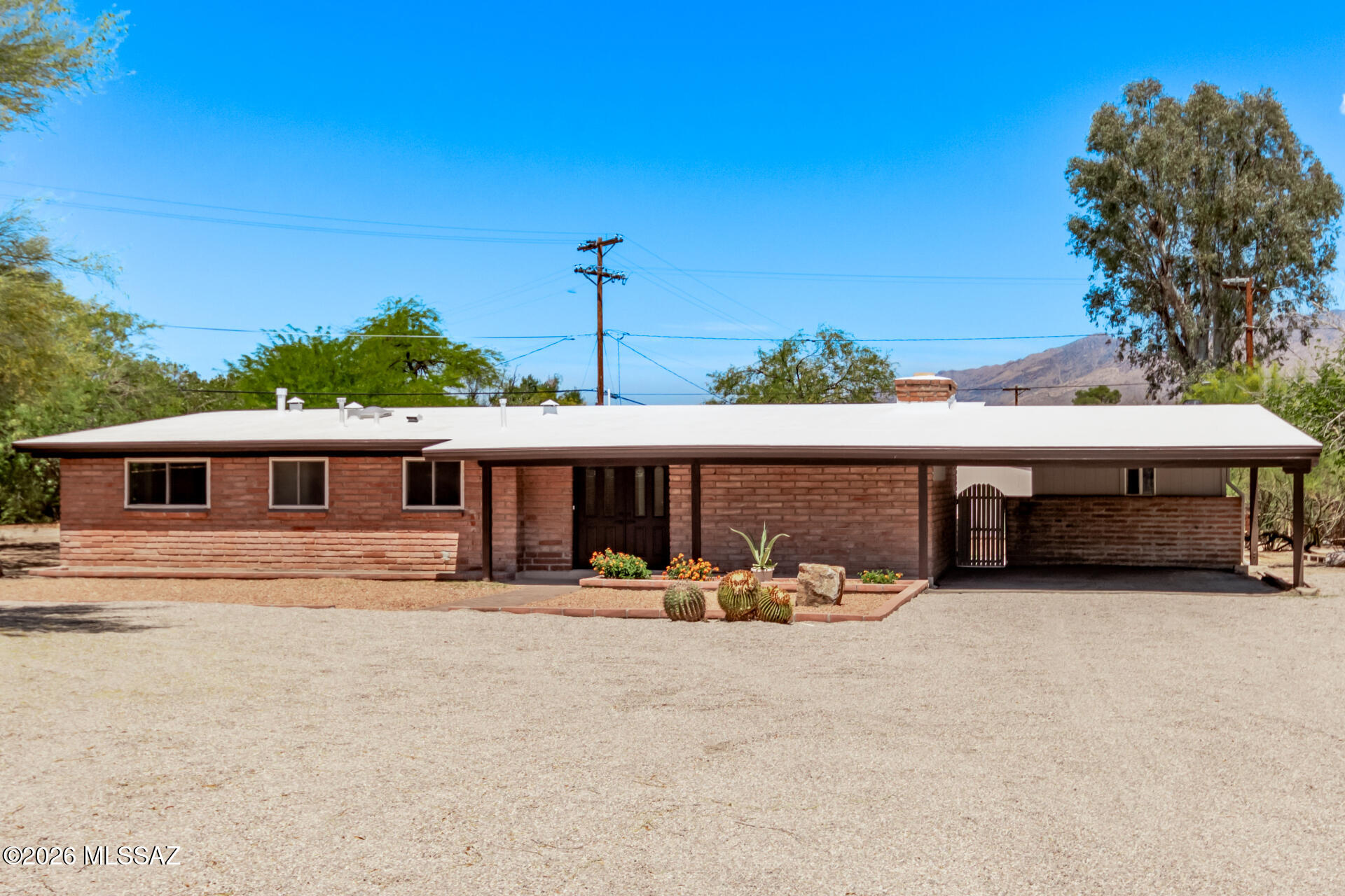 The home you've been waiting for! This beautifully remodeled gem offers mountain views, a low-maintenance front yard, attached carport, and welcoming covered porch. Step inside to a bright, open layout with exposed wood ceilings, updated fans, and new wood-plank tile flooring. The wood-burning fireplace creates a cozy focal point, while large sliding doors bring the outdoors in. The kitchen shines with nude wood cabinetry, custom subway tile backsplash, solid-surface counters, and an island with breakfast bar. Enjoy a formal dining room and two spacious primary bedrooms, each with a lavish bathroom-one with private entry. Expansive backyard ideal for entertaining, plus two detached storage rooms (As Is). What are you waiting for?! Agent/Owner.