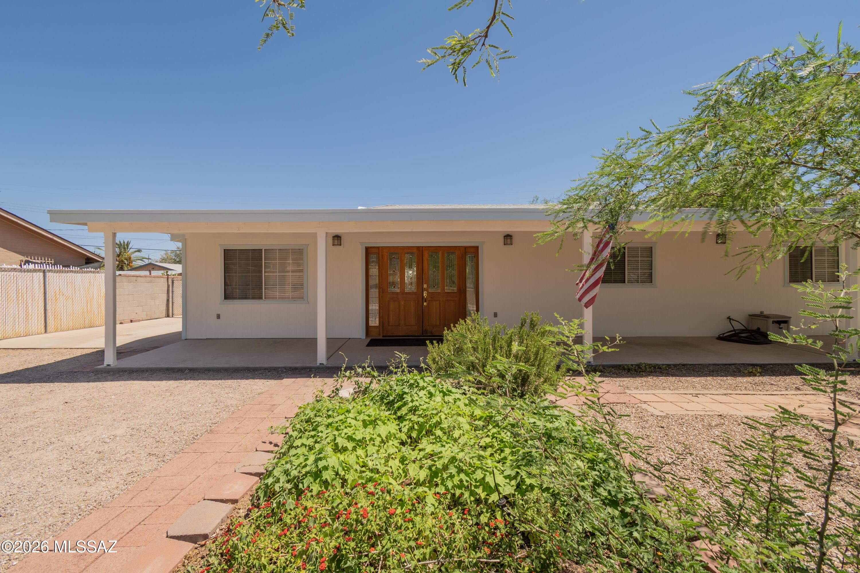 Charming East Side home in a convenient location close to the bus line, shopping, and dining. Recently painted and move-in ready, this property features an updated kitchen, tile flooring throughout with carpet in one bedroom, and abundant natural light. Elegant French doors welcome you at the entry and open to the backyard, creating a bright, inviting atmosphere. Enjoy full-length front and back patios, perfect for relaxing or entertaining. The fully fenced yard offers privacy and includes mature fruit trees in the backyard, along with mature trees and cactus landscaping in the front. A separate laundry room provides tons of storage space. The workshop/garage offers access from both the front and alley. Added insulation behind the siding helps improve energy efficiency and keep bills low