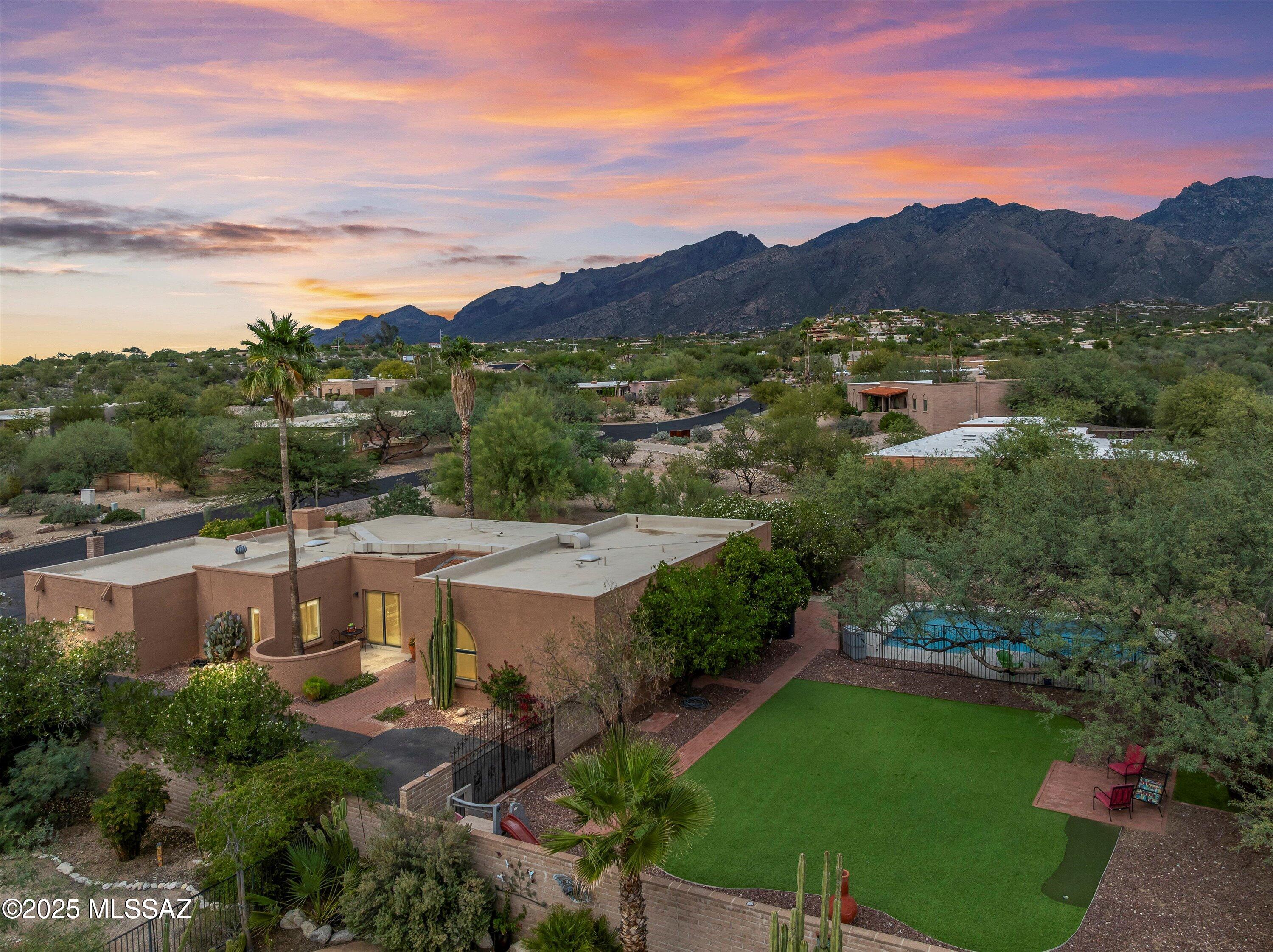 Discover sophisticated desert living at its finest in this meticulously maintained 2,501 sq ft contemporary home in the highly desirable Sunrise Presidio Village. Situated on over half an acre in a prime riparian corridor location, this 4-bedroom, 3-bathroom single-story residence offers the perfect blend of elegance, privacy, and natural beauty.
Positioned with the rear of the home facing north, enjoy unobstructed panoramic views of the majestic Santa Catalina Mountains from multiple vantage points throughout the property. Watch the mountains transform from grey to rose-gold at sunset—a daily spectacle that defines the Tucson experience. The property abuts a natural wash, providing exceptional privacy. This is true Sonoran Desert living.
Recent renovations have elevated this home while respecting its contemporary architecture. Elegant travertine stone flooring flows throughout main living areas, while bedrooms feature warm wood-look flooring. The gourmet kitchen showcases crisp white cabinetry, granite countertops, stainless steel appliances and pantry for exceptional storage. The kitchen window above the sink frames beautiful desert landscape views. The master suite features a generous arched window and mirrored closet doors. Abundant natural light streams through strategically placed windows and skylights, while a wood-burning fireplace creates cozy ambiance on cool desert evenings.
Two expansive gathering areas flow seamlessly together, perfect for hosting friends and family. The "mountain room" provides stunning Catalina views that become the focal point of every gathering. Formal dining room and off-kitchen living areas offer flexibility for various entertaining styles. French doors separate a large office/hobby room, ideal for remote work or creative pursuits.
The backyard is designed for the Arizona lifestyle. A rectangular pool with safety fencing is perfect for lap swimming and summer cooling. Artificial turf surrounding the pool requires zero watering and minimal maintenance. The massive walled yard features a covered patio facing north toward mountain views, with generous space for outdoor activities along sidewalks on west, north, and east sides. Mature landscaping includes towering saguaros, desert vegetation, and decorative river rock. A prolific grapefruit tree produces fruit almost every season, joined by additional citrus trees with rain harvesting barrels to reduce water costs. Low-maintenance xeriscaping demonstrates environmental responsibility without sacrificing beauty.
Enjoy the best of both worldseasy access to shopping, dining, medical facilities, and major thoroughfares, yet tucked away in a peaceful neighborhood with minimal traffic. The long paved driveway leads to a 2-car garage creating a private approach to the home with the entrance set back from the street for enhanced privacy. Curved entry courtyard with distinctive rounded wall adds architectural interest and shields the entry from view.
This home embodies the Catalina Foothills lifestylesophisticated, serene, and connected to nature. Whether enjoying morning coffee on the patio, swimming laps in your private pool, entertaining guests in light-filled living spaces, or watching the mountains turn pink at sunset, every moment reminds you why the Foothills is one of Arizona's most coveted addresses. Located in a riparian corridor just minutes from world-class hiking in Sabino Canyon and Catalina State Park, this property offers a rare combination of natural beauty and urban convenience perfect for evening walks and bicycle rides. As a bonus, the natural wash beyond the property line attracts abundant desert wildlife including Gambel's Quail, Cactus Wrens, multiple hummingbird species, javelina, and even bobcatsa front-row seat to the wonders of the Sonoran Desert.