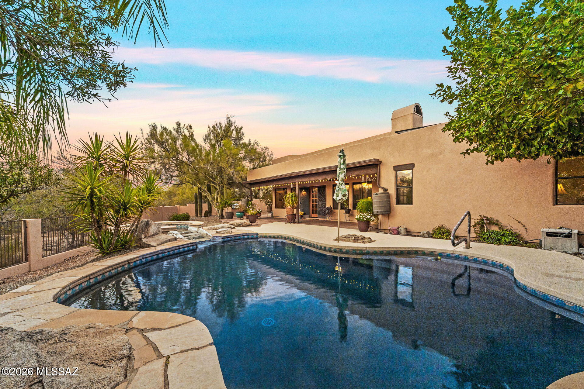 Santa Fe architecture paired with a resort-style backyard makes this home truly stand out! Situated on a nearly ½-acre lot in a desirable Northwest/Oro Valley location, this home blends character & comfort. The oasis-like backyard features lush landscaping, citrus trees, a built-in BBQ, sparkling pool & spa with UV disinfection system. Backing up to a well vegetated wash for privacy & breathtaking sunset views! Inside; soaring ceilings, wood accents, solar tubes & a classic beehive fireplace create a warm, inviting feel. The bright kitchen with black SS appliances opens to the great room & dining area. Split floorplan with 3 bedrooms, 2 updated baths & a 3-car garage. Leased solar offers energy savings. Community amenities include sand volleyball & picnic areas.