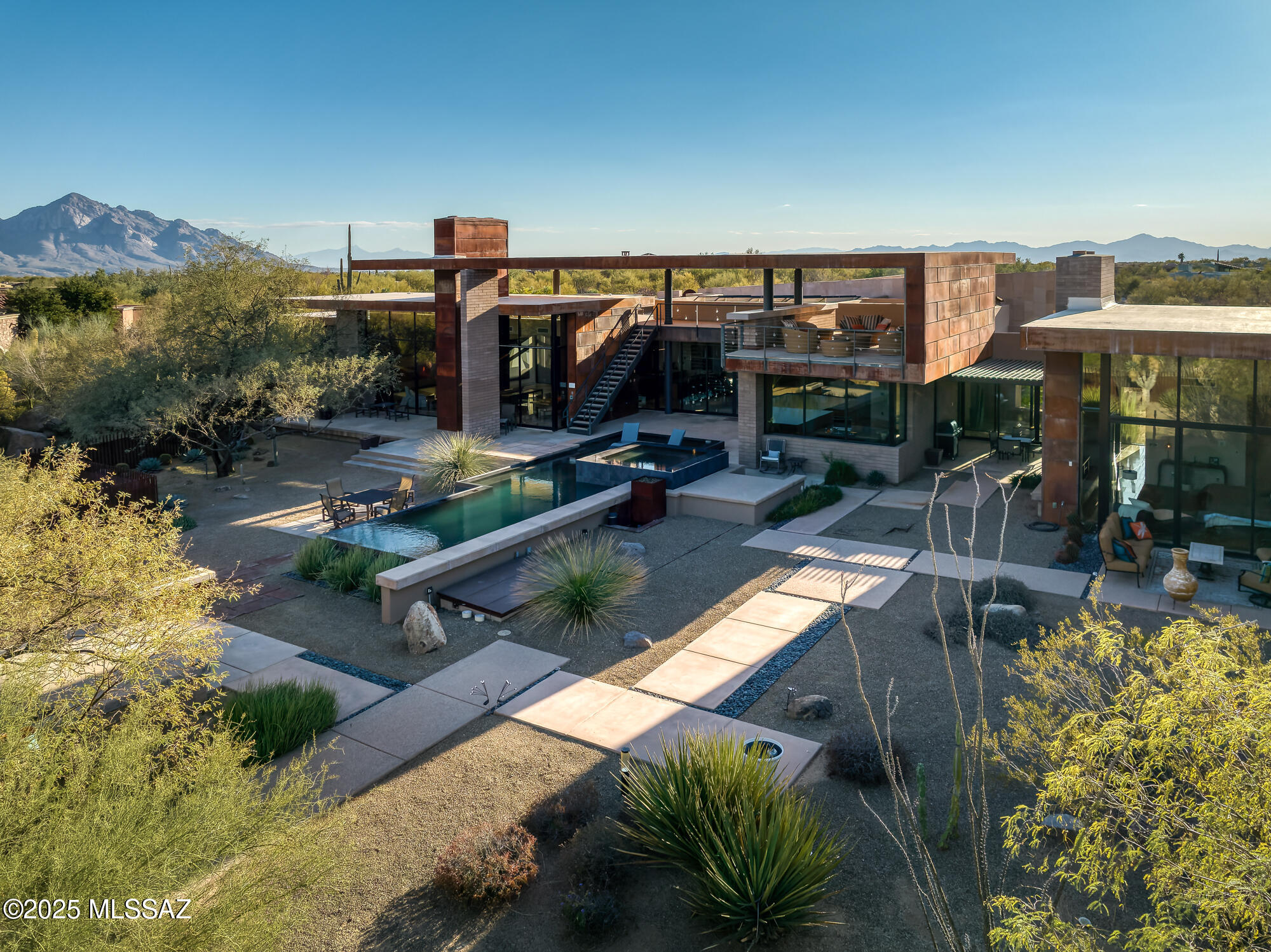 NEW PRICE! Welcome to a masterpiece of architectural brilliance at 474 W Tortolita Mountain Circle, a custom-built home nestled in the prestigious community of Stone Canyon. Designed by acclaimed architect Kevin Howard, this magnificent home offers a seamless fusion of luxury and modern aesthetics. Spanning nearly 6,000 square feet, the home showcases breathtaking views of the surrounding Catalina Mountains and the exclusive Stone Canyon Club's Hole #2, an exquisite Jay Morrish design. As you enter this one of a kind treasure, you're greeted by expansive glass walls that blur the boundaries between indoor and outdoor living. These disappearing walls are intertwined with the use of exposed masonry walls and ceilings of wood, metal, block and brick.  Sabbia Limestone flooring flows effortlessly throughout, complemented by sandstone finish walls, honed black granite and high-end Hansgrohe fixtures that exude sophistication and style. The open-concept design of numerous living areas that flow seamlessly together include a large living room which wraps into a family room and a kitchen designed for chef's featuring top-of-the-line Dacor and Wolf appliances, paired with a Subzero refrigerator, prep sink. warming drawer, commercial ice maker and oversized island. The exquisite master suite provides a sanctuary of luxury with a glass bead fireplace, an en-suite bathroom with a sumptuous soaking tub, a large shower, and convenient his and her sinks, toilets, and closets - complete with a stackable washer and dryer for added convenience, the suite's design emphasizes both comfort and privacy. Additional living spaces include a sophisticated office ideal for remote work or personal projects. 2 more bedrooms with en-suites complete this perfect split bedroom floor plan.  The detached guest house is a haven of convenience and style containing a cozy seating area, TV, Murphy bed, refrigerator, microwave, and bath with walk-in shower - perfect for hosting guests in comfort and privacy. An architectural gem that harmonizes opulence with nature's beauty and an added touch of Zen - note the custom designed landscaping with numerous water features, rock gardens and stepping stones surrounding the breathtaking negative edge pool and spa crafted specifically in black tile & pebbles.  Be prepared to be in awe of the 7,754-square-foot rooftop deck done in sandstone & metal that features an outdoor fireplace and TV. (Seller has prepared the home perfectly for the new owners - listed here is just a few of the numerous upgrades such as 3 new high efficiency hvac systems, pool equipment and pentair integrated app system, one year termite warranty, roof completely recoated 2025, sandstone tile installed on roof deck, flagstone patios, complete new irrigation system, custom barrier fencing,  plus owner owned solar system just inspected by Solar Store.)