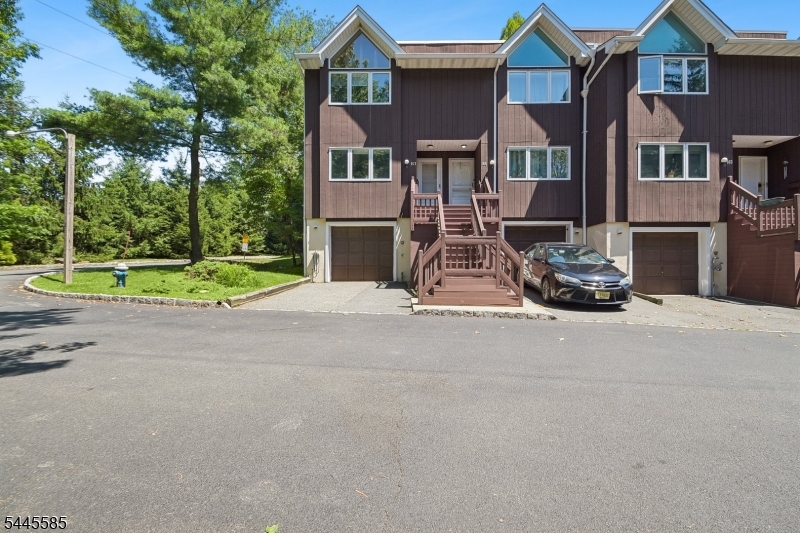Welcome to this beautifully maintained end-unit townhome in the desirable Essex Green Villas community. The inviting living room centers around a wood-burning fireplace with a rich wood mantel with sliders to your private patio, backed by mature trees and lush landscaping, perfect for grilling and entertaining. Gleaming hardwood floors carry into the sun-filled dining room, framed by leafy, private views, with elegant crown molding. The updated kitchen is both stylish and functional, featuring crisp white cabinetry, sleek countertops, a stainless steel gas range, dishwasher, and new refrigerator. A convenient powder room completes the main level. Upstairs, the primary suite impresses with dramatic vaulted ceilings, custom windows with wood plantation shutters, and an ensuite bath with a soaking tub, separate glass shower, and dual-sink vanity. A second spacious bedroom and an additional full bath with tub/shower combo offer comfortable accommodations for guests. The finished lower level adds fantastic bonus space, along with a dedicated laundry room. commuters will love the location: easy access to NYC via free jitney service to the train, plus close to major highways. Residents of Essex Green Villas also enjoy community amenities including an in-ground pool and courts. Recent upgrades include: new windows, custom window treatments, dual-zone HVAC, appliances, and water heater. This is a wonderful opportunity to own in in this sought-after community. Welcome Home!