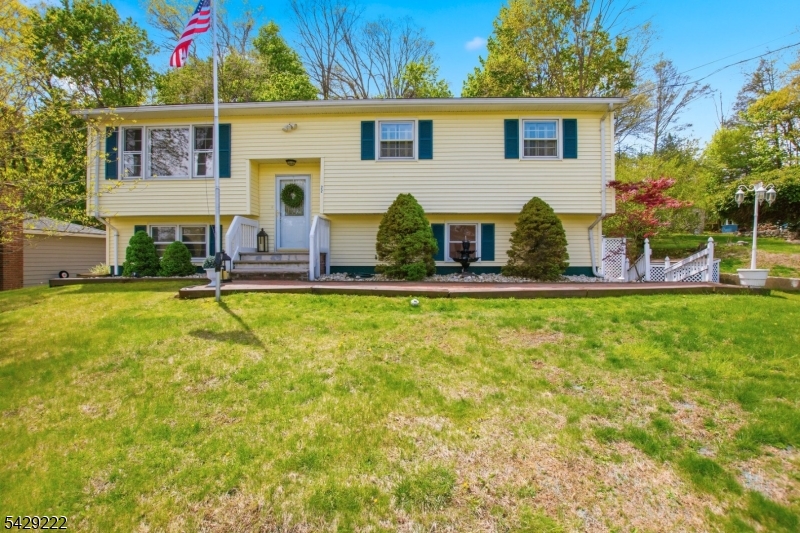 Welcome to 22 Holiday Drive, perfectly positioned atop the mountain with beautiful front-yard views of Lake Hopatcong and deeded boat docking rights. This impeccably maintained 3-bedroom, 2-bath bi-level home offers approximately 1,900 square feet of living space and reflects true pride of ownership throughout. The property features stunning landscaping and an entertainer's dream backyard, complete with three deck platforms and a built-in propane tank to fuel outdoor grilling. The main level showcases hardwood flooring throughout the living room and three bedrooms, along with a full main bath. The kitchen features a breakfast bar overlooking the formal dining area, with sliding doors leading to the upper deck where you can enjoy scenic lake views. The ground level offers a spacious family room with a cozy free-standing fireplace and French doors opening to the lower deck and backyard. This level also includes a bonus room, a utility room with laundry, and an attached one-car garage. Additional updates such as new AC, vinyl siding, Anderson slider, custom shades, and new metal leaf guards provide added comfort and peace of mind. Experience lake living at its finest and enjoy the lifestyle that Lake Hopatcong has to offer.