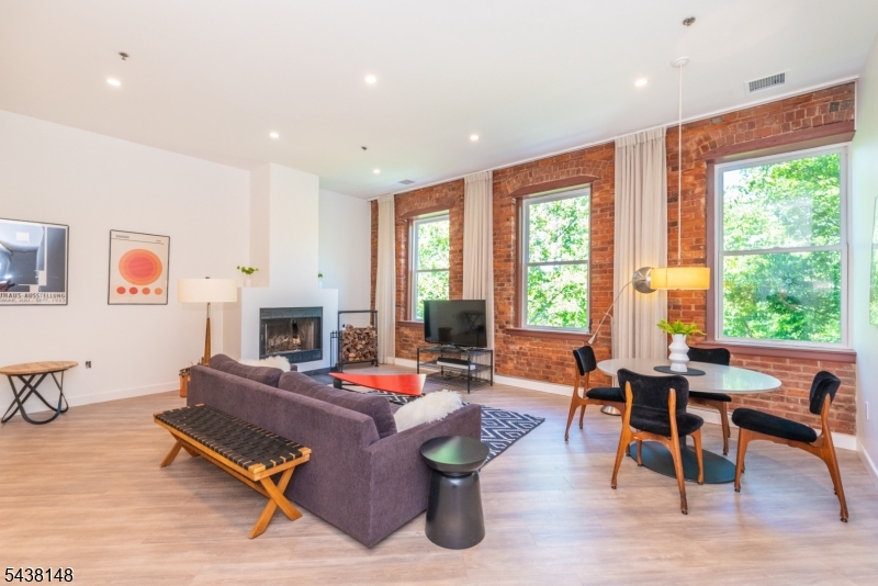 Set against a picturesque riverfront view, this unique top-floor corner condo showcases one of The Mill's most unique architecturally distinctive residences. Extensively renovated, this two bedroom two bath residence offers approximately 1,156 sq. ft. of updated living space with loft like high ceilings. Three oversized windows framed by exposed brick create a dramatic focal point in the main living area, which also includes a wood-burning fireplace. The newly renovated kitchen features modern kitchen cabinetry and quartz countertops. Both baths are fully renovated, and the oversized windows have been upgraded, improving efficiency. The primary bedroom suite is centered by the standout feature of a unique arched picture window, and includes walk-in closet, and a private en-suite bath. The second bedroom overlooks the river, has a large closet with two overhead storage compartments, and is serviced by a renovated hall bath, and dedicated utility/laundry room. Positioned on the top floor and benefiting from its corner location, the condo feels private with waterfall views and treetop vistas. Residents of The Mill enjoy nearly 12 acres of maintained grounds and amenities, including a clubhouse, fitness center, tennis courts, swimming pool, and walking paths. Located right near restaurants, major shopping, highways, with door front NYC public transportation.