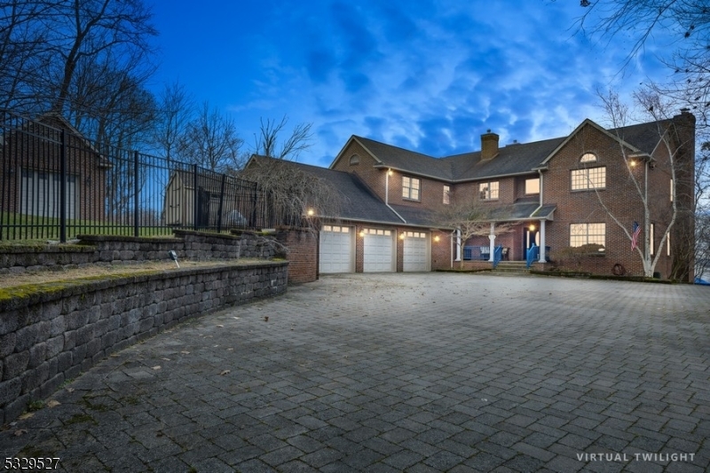 An impressive mini estate welcomes you through an iron gate entry, unveiling apprx. 340 feet of pristine lakefront on 5.2 private acres. The grand foyer leads into a 5,000+ sq ft home, where elegance meets comfort. The formal living room with a wood-burning fireplace flows into the dining room, featuring a double-sided gas fireplace. A cozy family room offers another gas fireplace. The gourmet kitchen boasts high-end appliances, solid wood cabinetry, double sinks, double ovens, a commercial range, granite countertops, a pantry wall, and a breakfast room. A powder room near the office allows for a first-floor bedroom option. The grand primary suite features two walk-in closets, a spa soaking tub, a double shower, and dual sinks, with four additional bedrooms, including a fifth en-suite.  The finished walk-out lower level includes a recreation room, a sixth bedroom/bonus room with full bath potential, wine cellar, and hobby room. Outside, enjoy an expansive covered porch, 20x40 heated pool, patio, and detached garage/pool cabana. A serene sitting area at the water's edge offers a patio, docking for several boats, a private launch for kayaks,  jet skis, and the opportunity to build the boat house of your dreams and complete this lakefront retreat. Enjoy lake life beyond your property and visit restaurants by boat, fish, swim, skate, and snowmobile. Several hiking trails, and tennis courts/parks. NJ's largest lake offers four seasons of enjoyment all just one hour to NYC.