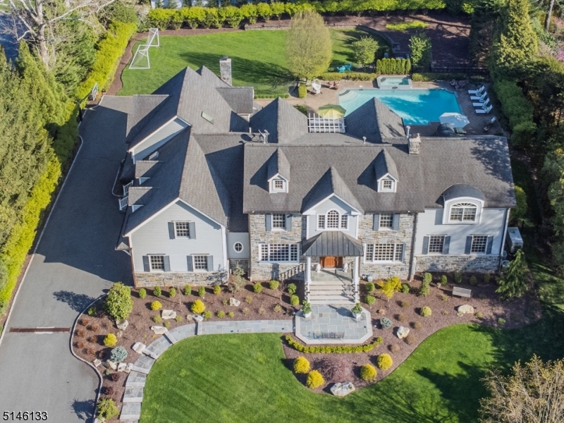 You'll never need to leave for the Hamptons in this exquisite Short Hills home that delivers resort living right outside your door. Enjoy a seamless flow to manicured grounds that beg to host your next wedding and neighborhood barbecue. Inside, the layout creates a smart separation between entertaining space and private quarters, while handcrafted millwork, Brazilian cherry floors and designer wallpaper run throughout. Bring the outdoors in with abundant double-paned Weather Shield windows and custom French doors that open nearly every room to the expansive covered flagstone patio, updated pool and spa, sun deck, lush lawns and landscaping. Inside, the double-height foyer opens to a living room and vast media room with a two-sided fireplace, walk-up bar and projection system. A formal dining room and butler's pantry lead to the chef's kitchen filled with full-feature cabinetry and elite Wolf Miele and Sub-Zero appliances. A family room, mudroom, pool bath and laundry complete the level. Above, a sprawling owner's suite includes an office, dressing room, en suite spa bath and balcony. Luxurious secondary bedrooms include two suites, two beds with a Jack-and-Jill bath and a sixth bedroom that opens to a balcony. A large laundry room and storage add convenience here. On the fully finished lower level, palatial rec room areas lead to another bed and bath. Zoned HVAC, generator, upgraded electrical, central vacuum, alarm, Sonos speakers, three-car garage with EV charging.