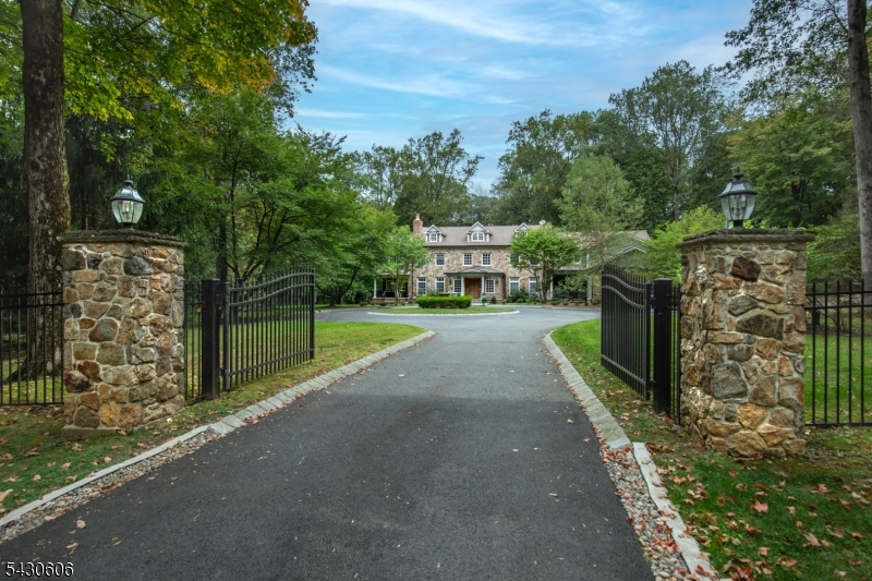 This Custom Colonial provides over 8,400 square feet of meticulously designed living space, situated on 6.5 level acres in a premier Mendham Township location. The interior showcases high ceilings, detailed millwork, and a blend of hardwood and stone flooring. The floor plan supports both grand entertaining and comfortable daily life. The heart of this home is a chef's kitchen that flows into a grand family room, creating an inviting central hub. The formal dining room and a bright conservatory offer distinct environments for entertaining guests. A handsome library provides a quiet workspace, while the first-floor guest suite ensures convenience for visitors. High-end finishes continue into the primary retreat, which boasts a private sitting area, dual walk-in closets, and a spa-like bathroom. The walk-out lower level is designed for recreation. This finished space includes a family room with a fireplace, an exercise area, and a dedicated wine cellar with a tasting room. Modern infrastructure includes a built-in Generac generator, central vacuum, and a comprehensive security system. The exterior grounds provide a peaceful sanctuary with wooded perimeters and manicured open lawns. An outdoor fireplace and multi-tiered decks make the backyard a destination for alfresco meals. Located just a short drive from the Midtown Direct train in Morristown, this property combines a serene country setting with easy access to urban conveniences and highly regarded educational institutions.