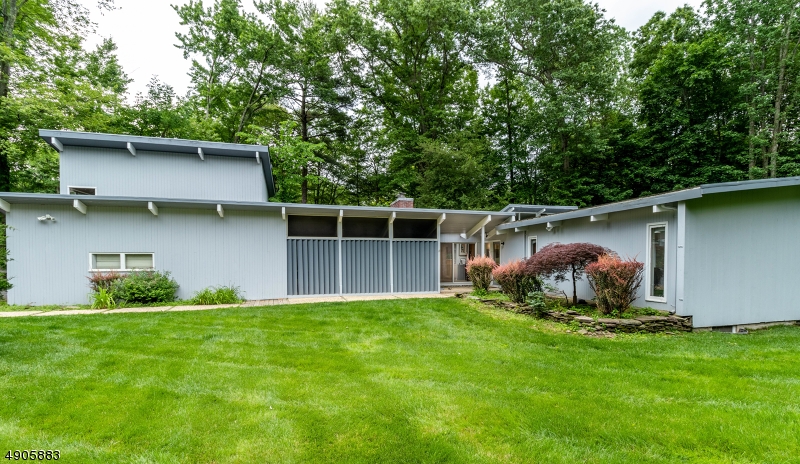 4 bedroom, 2 bath mid-century/ modern contemporary home w/ country feel, close to Morristown shopping & NYC train. Open floor plan, nestled on a wonderful park-like setting. Hardwood floors throughout & great views from every room. Master bedroom has an en-suite bath & 3 additional bedrooms w/ one currently being used as a office. Modern kitchen w/ ss appliances & built in wine fridge, w/ center island. The large family room provides plenty of space for entertaining.  There is an extra bonus building, w/ two floors which can be used as a workout area & craft or hobby room. There is a full greenhouse & a covered porch/3 season room. A one car attached garage, w/ parking for 6 additional cars & partially finished basement complete this home.