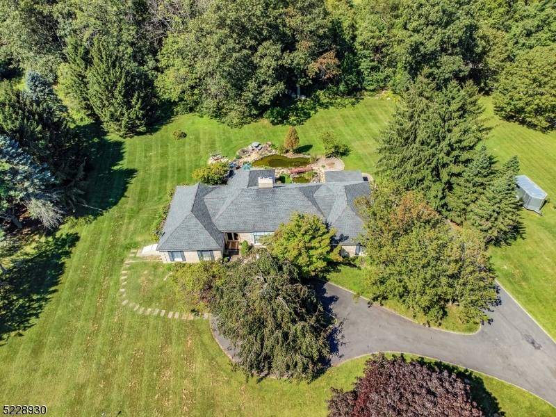 Peaceful single floor living with tremendous lot and more! Set well off the road, pull up the circular drive with Belgian block curbing and immediately feel at home! Almost 3 acres of open and usable space including koi pond and upgraded septic system includes new tanks, engineering and approvals!! Double door entry leads to ceramic tile foyer and living room with hardwood flooring and woodburning fireplace. Through French doors is the formal dining room. Large eat-in kitchen with breakfast area features granite counter tops, stainless steel appliances, pantry and French doors to patio. family room has hardwood floors and woodburning stove, sky tunnels for additional natural light and leads to 3 season room, adjacent to patio. The bedrooms are set off of a private hallway with main bath, and spacious primary suite with sauna, and full bath with stall shower and tub. Enormous basement is mostly finished with rec room, full bath, home office and has Bilco doors to the side yard. All of this located within Washington Twp. with superb schools and acclaimed West Morris Central High School with IB Program. Roof approximately 10 years old with 30 yr guarantee, central air, furnace replaced 2019, propane generator; Water heater, oil tank, monitor, heat all Wi-Fi enabled; electric heat is secondary source of heat in the finished portion of basement only.
