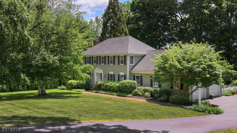 Craftsmanship and quality shine throughout this exceptional four-bedroom custom Colonial, beautifully set on 1.15 acre of meticulously landscaped grounds. A welcoming foyer with a sweeping staircase makes a memorable first impression, while hardwood floors, detailed moldings, and timeless architectural features add warmth and character throughout the home.The spacious front-to-back living room features a wood-burning fireplace, while the formal dining room flows seamlessly into a custom wet bar with cherry cabinetry, glass-front cabinets, a built-in wine rack, and a hammered copper sink. The gourmet kitchen is equipped with custom cherry cabinetry, granite countertops, stainless steel appliances, walk in pantry, and eat in area with French doors leading to the deck. Openly connected  to the kitchen, the inviting family room offers beautiful millwork and a cozy gas fireplace. Upstairs, the expansive primary suite includes a walk-in closet and updated bath. Three additional bedrooms and a full hall bath complete the second level. The bright walkout lower level provides a large recreation room with door to the backyard. Outdoor living is equally impressive, with a spacious deck overlooking a fenced garden patio,  colorful perennial plantings, and mature landscaping. Lovingly maintained and move-in ready, this home offers public utilities, exceptional curb appeal, and a convenient location close to town, top-rated schools, and NJ Transit.