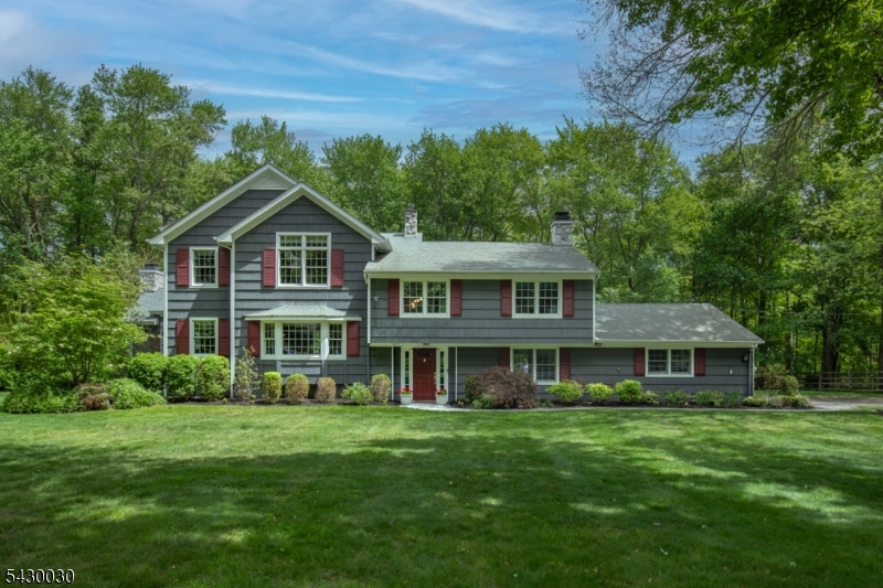 Expanded and beautifully maintained 4 bedroom, 3.5 bath home set on 0.93 acres in a quiet section of Basking Ridge known for its large lots, mature trees, and peaceful park-like setting. The home has been thoughtfully renovated over the years and offers generous living spaces throughout. A truly standout feature of the home is the stunning family room addition with a beautiful stone fireplace, custom built-ins, and walls of windows extending through the breakfast area overlooking the mahogany deck and private backyard. Filled with natural light, this space creates a beautiful connection to the outdoor setting. A second fireplace in the den adds another inviting space to relax and unwind. A hot tub adds to the enjoyment of the backyard and deck area. The oversized kitchen with abundant countertop space and extensive cabinetry offers room to cook, entertain, and gather. Additional highlights include a dedicated first-floor office, a finished basement with high ceilings, and an impressive primary suite with two large walk-in closets. Mature trees, peaceful outdoor spaces, and a quiet neighborhood setting give this home a warmth and sense of retreat that make it a wonderful Basking Ridge home. As per tax records home is 3643 square feet.