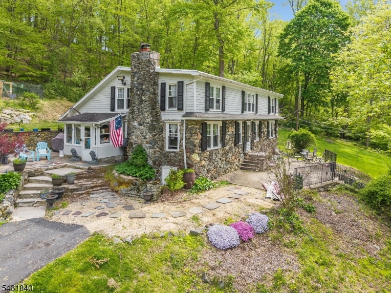 A STONE FRONT CIRCA-1885 HILLSIDE BANK-HOUSE COLONIAL WITH A SEPARATE RENTAL COTTAGE AND A SMALL HEATED GYM ON A GORGEOUS 7.90 ACRE FORESTRY-ASSESSED LOT WITH A GREAT LOCATION A FEW HUNDRED YARDS DOWN  THE ROAD FROM THE FABULOUS MILES OF HIKING & BIKING OPPORTUNITIES OF THE FABULOUS COLUMBIA TRAIL, AND JUST ROUND THE CORNER FROM THE PRISTINE FREE-FLOWING TROUT-FILLED  WATERS OF THE SOUTH BRANCH OF THE RARITAN AS IT FLOWS THROUGH THE SPECTACULARLY SCENIC FLY-FISHING MECCA OF THE KEN LOCKWOOD GORGE. THE CENTERPIECE HOME OF THIS UNIQUE COUNTRY COMPOUND FEATURES A HUGE 15X15 BEAMED-CEILING COUNTRY KITCHEN WITH SOME STAINLESS APPLIANCES AND AN ATTRACTIVE SUBWAY TILE BACKSPLASH, THE HOME ALSO FEATURES A GREAT WIDE-OPEN FLOOR PLAN IN FRONT WITH A RAISED-HEARTH FLOOR-TO-CEILING STONE FIREPLACE IN THE FAMILY ROOM SECTION AND A FULL WALL OF WINDOWS AND BUILT-IN BOOKSHELVES IN THE DINING ROOM PORTION OF THE IMMENSE ROOM. ALSO ON THE FIRST FLOOR IS A POTENTIAL FIRST FLOOR IN-LAW SUITE COMPLETE WITH A SMALL BEDROOM, A FULL BATH, & AN ACCESSORY KITCHEN. THE SECOND FLOOR OFFERS AN ENORMOUS 22X16 MASTER BEDROOM, THREE EXTRAORDINARILY OVER-SIZED SECONDARY BEDROOMS, AND A SHARED HALL BATH. THE SEPARATE COTTAGE OFFERS A SINGLE BEDROOM, A FULL BATH, AND A LIVING ROOM WITH A LARGE VIEW-FACING PICTURE WINDOW AND A FIREPLACE. LARGE MULTI-LEVEL PATIOS ADD TO SUMMER FUN & DINING OPPORTUNITIES.