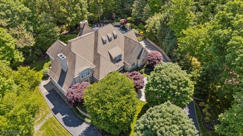 25 Knightsbridge, nestled lakeside in Watchung's "Burnheade" neighborhood, offering a private lot enveloped by the natural beauty of surrounding trees. This property is a serene retreat just minutes from Route 78. You'll be enchanted by the grand entry hall, featuring soaring ceilings, herringbone-patterned hardwood flooring, & custom millwork. With 5 bedrooms, 6 full and 2 half baths. The chef's kitchen is a culinary delight, equipped with a separate Sub Zero refrigerator & freezer, 2 Miele dishwashers, a Dacor stove & wall oven, Sub Zero refrigerator drawers & limestone-granite counters. The solarium overlooks your backyard oasis, featuring a heated saltwater pool. The great room has a floor-to-ceiling stone fireplace, coffered ceilings, & a wet bar, creating an amazing space for gatherings. The elegant office/library is highlighted by a gas fireplace & panoramic views of the private property. The finished walk-out lower level has an additional apartment-style living space, complete with its own entrance, living room, kitchenette, ensuite, & laundry closet. The LL (with 2 full baths) also features a wall of windows & doors that connect to the stone patio, offering a seamless indoor-outdoor flow for hosting large gatherings. For added convenience, the property boasts an elevator, a security system, & three laundry room areas, ensuring practicality for daily living. The 14-zone heating system, 7-zone A/C & 5 fireplaces add to the allure of this residence. Welcome home.