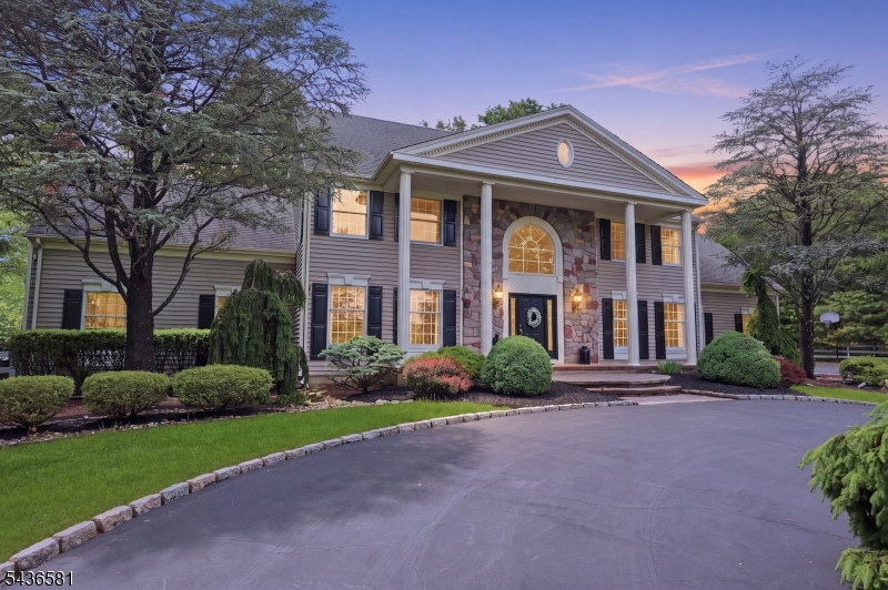 Positioned at the end of a quiet cul-de-sac this custom colonial pairs standout architecture with a private lot abutting 18 acres of preserved open space. From the sweeping circular drive and grand columned portico to the soaring interiors, the craftsmanship reads immediately. Inside, the two-story foyer opens to a graceful staircase and formal living and dining rooms. At the center, a chef's kitchen boasts ceiling-height cabinetry, premium appliances, and oversized island designed for everyday living - opening to a spectacular great room, where cathedral ceilings and a floor-to-ceiling stone fireplace create a dramatic focal point. Custom-milled cabinetry adds architectural finish, while arched windows frame the wooded backdrop and French doors lead to the outdoor living space. A private office, powder room, and mudroom/laundry with garage access complete the main level. Upstairs, the primary suite features furniture grade cabinetry, a walk-in closet, and artisan-crafted iron-railed Juliette balcony overlooking the great room. The en suite is complete with a soaking tub, shower and dual vanities. Three additional bedrooms and a hall bath complete this level. The lower level extends the home's versatility with a wine cellar, studio, playroom/gym and workshop. Outside, fieldstone walkways lead through the lush grounds to an expansive composite deck built for long outdoor seasons and low-maintenance living. Minutes to top rated schools, Stanton Ridge CC and Rt.22/78.
