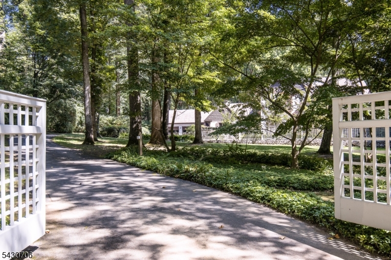 Down a long private road, this custom home offers peaceful privacy and luxurious living spaces on 3 acres in Harding Township.  The beautiful courtyard welcomesyou to the front of the home.  The layout flows from the front foyer to a large formal living room with wood-burning fireplace and floor to ceiling windows.  The large custom kitchen has a center island and separate breakfast room overlooking the spacious family room with built-in bookshelves and wood-burning fireplace.  A large formal dining room with your third wood-burning fireplace and floor to ceiling windows is connected to the enclosed sun-room with expansive views of the lovely yard and pool.  The main floor is finished with a large pine paneled office and separate powder room.  The interior of this home exudes warmth and charm with hardwood floors throughout.  The second floor includes a palatial primary suite with a sitting room and en-suite bathroom as well as walk-in closets.  There are 3 additional bedrooms one of these is en-suite while the other two share the hall bathroom.  The laundry room finishes off the second floor.  The walk out lower level has more living space a tv room, game room, wet bar with ice maker, dressing room and full bath.  There is also a storage room with access to the attached 2 car garage.  There is an additional 2 car detached garage as well.  The completely deer fenced property includes a vegetable and herb gardens, custom multi-level decking and a beautiful in-ground pool.