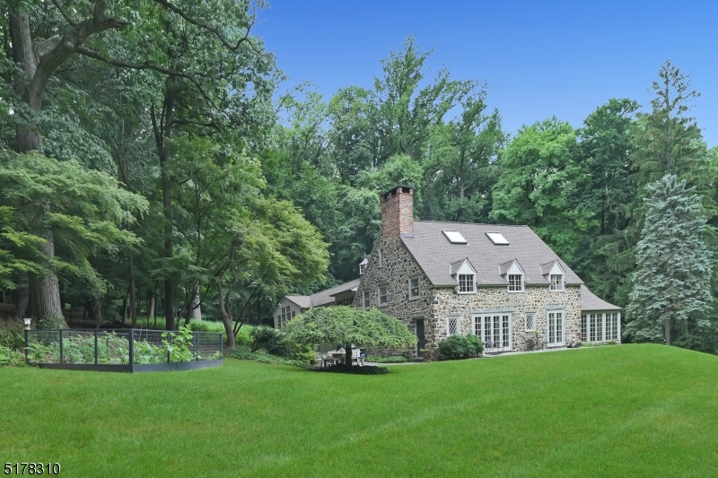 A truly special 6 BR, 4.5 BA stone homestead on nearly 5 acres in the historic neighborhood of Llewellyn Park. W/ direct train access to NYC only 6 minutes away, it's an easy commute from NJ's most desirable +oldest gated community, w/ 24-hour guard house. Custom stonework + exposed beams separate the decked out kitchen from the breakfast nook + countertop bar seating. A massive primary BR, complete with a huge walk-through dressing room, Birdseye maple wood floors + stone gas fireplace, is drenched in sun courtesy of two ceiling skylights. On the 1st fl, an in-law or nanny suite opens to the outdoors through a separate entrance + includes a sitting room + full bath. A large built-in theater room for entertainment. On the 3rd fl, a bright, airy office space is perfect for a work-from-home set-up. In the basement, you'll find a photographer's dark room, laundry + an additional living/playroom. The stunning grounds are landscaped to perfection and include a flagstone patio. Located minutes from Montclair shopping + dining.