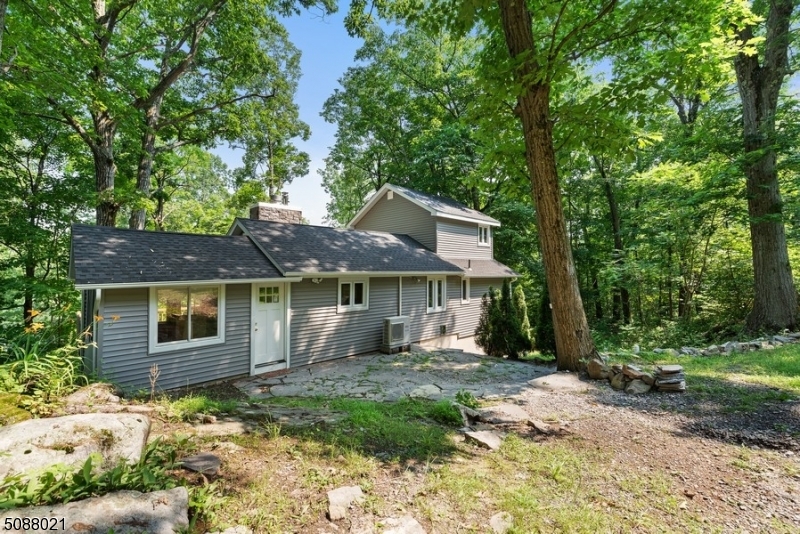 Natural beauty all around you in this charming home w/ 2 BR, 1 bath, & an amazing deck w/ seasonal lake views! This cozy cottage is nestled on nearly an acre of private property just minutes to East Highland Lake where you can enjoy boating, fishing, kayaking, beaches, & all this lake community has to offer. From the front patio, step inside to an enclosed porch w/ an entry directly onto the back deck & another into the spacious kitchen w/ ample counter & cabinet space & a breakfast bar. The open layout in the living/dining room showcases a beautiful floor-to-ceiling stone fireplace & windows all around overlooking the lush greenery. The main level continues with a full bath & primary bedroom w/ a walk-in closet. There is a second BR upstairs, & a full basement offers great potential for expanding.