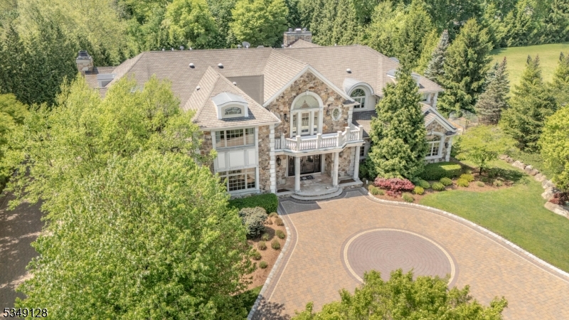 Once in a lifetime opportunity to own one of North Caldwell's most iconic estates. 11 Rickland Drive is a magnificent custom home built in 2009 with over 11,000 square feet of luxurious living across 30 thoughtfully designed rooms. No expense or detail was overlooked. Grand in scale yet warm in ambiance, this residence is perfectly suited for large-scale entertaining or intimate gatherings. The home offers seven bedrooms, each with a private ensuite, along with a total of nine full and two half baths. A dramatic dual staircase, soaring ceilings, arched passageways and rich millwork set the tone, while designer finishes and multiple interior balconies add elegance throughout. The main level features a gourmet kitchen with a breakfast room and an oversized island, formal living and dining rooms, a vaulted sunroom, a richly appointed office with a fireplace, a great room with a balcony overlook, a cabana room with a wood-burning fireplace and full bath and a state-of-the-art theater. An elevator services all three levels. Upstairs, the primary suite includes a sitting room, dressing room, double walk-in closets, two water closets, an adjoining den with kitchenette and a private balcony. The lower level offers a dance floor, bar, kitchen, gym, spa, arcade, lounge areas and guest suite. Outside, 2.37 acres unfold into a resort-style setting with a heated pool, water slide, waterfall, covered bar, firepit, patios and manicured grounds.