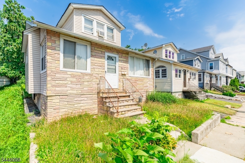 Classic dormered 1.5-story home on a 35x100 lot in Irvington offers 4 bedrooms, 2 full baths, and 7 rooms across multiple finished levels. Hardwood floors with decorative inlay borders anchor the living room, flowing into a formal dining room with a china-cabinet wall and an eat-in kitchen. An enclosed porch with a wood plank ceiling adds flexible mudroom or storage space, and the finished upper-level bonus room offers additional living area. The finished basement expands the footprint. Stone veneer and vinyl, an asphalt shingle roof, a built-in 1-car garage, and public water and sewer. Convenient to schools, shopping, houses of worship, NYC transportation, and the Garden State Parkway.