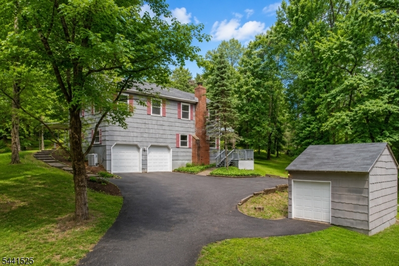 Rare opportunity to own a private 3.09-acre property offering space, privacy, and versatility just 15 minutes from both downtown Hillsborough and Flemington. Set well back from the road and surrounded by mature trees, this spacious split-level features a 3.5-car garage capacity with an oversized 2-car attached garage with loft storage plus a detached 1.5-car garage/workshop with electricity. The walk-out lower level, on the same level as the attached garage, includes a large workshop with built-in storage, industrial shelving, and a commercial-grade stainless steel triple-basin utility sink. Enjoy outdoor entertaining on the approximately 1,000 sq. ft. multi-level deck and covered patio featuring an outdoor ceiling fan, oversized propane grill, and stainless steel prep station. Inside, you'll find hardwood flooring throughout much of the home, a family room with a wood-burning fireplace and new luxury vinyl plank flooring, and a primary suite with dual step-in closets and a private bath. Additional features include a whole-house attic fan, 2-zone central air, 3-zone heating, 200-amp electric service with generator transfer switch, portable generator and hook-up, plus natural gas available for future connection. Recent improvements include a new GAF architectural roof with transferable 50-year warranty (2026), new garage doors and openers (2026), and septic system tested and passed (2026). Some photos have been virtually staged.