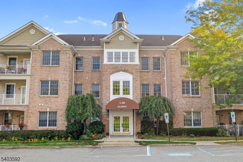 Enjoy effortless living in this desirable active adult community offering a clubhouse, pickleball courts, fitness center, pool, scenic walking paths, and more. This well-appointed first-floor condo provides easy, step-free access from the main entry ideal for everyday convenience. Thoughtfully positioned, the unit enjoys peaceful wooded views from the kitchen, living room, bedrooms, and enclosed porch, creating a private, natural backdrop. Inside, the open kitchen features ample cabinetry, updated appliances, and generous counter space perfect for both daily living and entertaining. The bright dining and living room combination is filled with natural light and opens directly to the balcony. Just off the living area, a versatile bonus room offers flexibility as a home office, den, or creative space to suit your needs. The primary suite includes a walk-in closet and an updated walk-in shower designed for comfort and ease. The second bedroom also features a walk-in closet and its own full bath, ideal for guests. A dedicated laundry closet with full-size washer and dryer (all appliances included) provides excellent storage as does the pantry. Additional highlights include an assigned garage space,guest parking directly in front, private storage unit for seasonal items, and elevator access within the building.With a spacious layout, smart floor plan, and access to resort-style amenities, this home delivers both comfort and convenience.Some photos digitally enhanced.