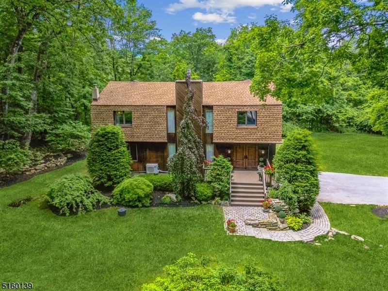 On vacation at home, all year long! You'll be captivated by this spacious & stunning Contemporary Chalet home nestled on 1.7 private acres in scenic Vernon Township. Enjoy peaceful privacy in this bucolic community w/easy access to local shops, eateries, schools, parks & Mountain Creek Resort offering skiing, snowboarding & a waterpark. Designed to take full advantage of its rural setting, this spectacular home encompasses 3 Bd, 2 1/2 Bths & an attached 2-car garage. The generous, open-plan interior features rich oak hardwood floors & trim work, 2 fireplaces & large windows w/sweeping views of the grounds. The beautifully landscaped front yard & walkway lead to a charming front porch entry. Inside, the vestibule opens to a LR w/French doors to a screened-in porch offering treetop views, adjacent the stunning FR w/vaulted ceilings filled w/natural light showcasing a magnificent natural stone fireplace flanked by 2-story windows. The gourmet eat-in kitchen will inspire your inner chef with its top-of-the-line appliances, granite counters, custom cabinetry, center island & arched greenhouse window. The breakfast nook has built-in glass-fronted cabinets & sliding glass doors to the porch & deck. The 2nd flr includes a stunning primary Bd suite w/a fireplace, floor-to-ceiling windows & en-suite Bth. 2 addt'l Bds share a full hallway Bth w/an oversized glass shower & clawfoot soaking tub. The basement level offers access to the garage, extra storage & a walkout to a covered patio.