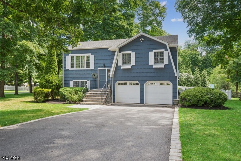 Situated in a sought-after Basking Ridge neighborhood, this exceptional bi-level residence blends timeless elegance with modern comfort. Hardwood floors, plantation shutters, and crown and picture-frame moldings enhance the thoughtfully designed floor plan. Graceful columns define the transition from the living room to the dining room, creating effortless flow for daily living and entertaining. The renovated kitchen by Zook Kitchens showcases fine craftsmanship and quality finishes. At the heart of the home is the breathtaking family room, where a vaulted, beamed ceiling and a dramatic wall of windows fill the space with natural light and frame serene views of the private grounds. Three bedrooms and a full bath complete the main level. The lower level offers a rec room, a versatile bedroom/office, and a luxurious primary suite with a coffered ceiling, recessed lighting, a walk-in closet, and a spa-like bath with dual vanities and a steam shower. A second full bath with laundry adds convenience. Outside, the beautifully landscaped yard is a true sanctuary, featuring an expansive deck and a large, paver patio with a dedicated gas grill line - perfect for entertaining or quiet relaxation. An attached two-car garage with a spacious crawl area provides abundant storage. Recent updates include: new 75- gallon water heater, A/C unit, KitchenAid range & Miele dishwasher. Just moments from downtown Basking Ridge, the train station, and bus service, this home is a commuter's dream.