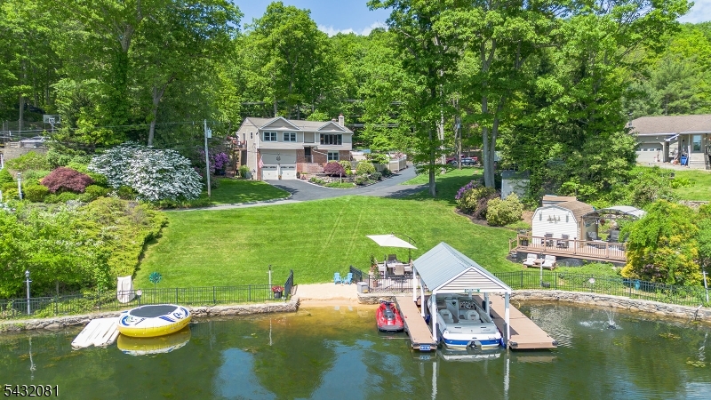 Welcome to your private Lake Hopatcong retreat!  Set on 1.2 beautifully landscaped acres with an incredible 135 feet of lake frontage including a covered boat dock, this exceptional home offers the perfect blend of privacy, nature, and lakefront living. The quiet cove location keeps waves and noise at bay while the small sand beach area adds fun for all. The lake front space offers a perfect gathering space for entertaining with a lawn, deck and patio for wonderful summer days and nights. The back feels like you've entered a retreat center with beautiful walking paths, peaceful waterfalls and pond.  The additional decking and patio makes for multiple gathering places designed to please. Inside, the home offers a warm and inviting layout with large windows that capture breathtaking lake views while spacious gathering areas flow seamlessly to the outdoors. Many recent updates including 2 baths, new balcony off the MBR, roof, siding, gutter, chimney liners and more.  This park-like property creates a resort-style setting rarely found on Lake Hopatcong, with mature landscaping, natural stone accents, and multiple areas to relax and enjoy the beauty of nature and the lake.  Whether you're looking for a year round residence, the ultimate weekend getaway or a place to rent to others, this one of a kind property offers an extraordinary lifestyle experience on New Jersey's largest lake.