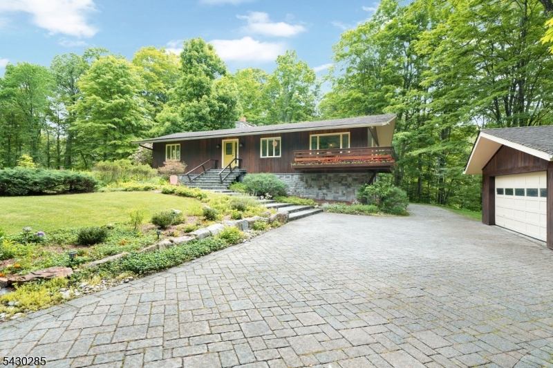 Discover a truly exceptional property in desirable Montville Twp., where privacy, nature & comfort come together on 1.54 picturesque acres. Nestled between protected Highlands Act land & Green Acres, this custom-built 4-bedroom, 3-bath home offers a peaceful retreat surrounded by breathtaking natural beauty. Enjoy coffee on the terrace, relax by the fire pit, or explore nearby hiking trails just steps away. Designed to blend harmoniously with its wooded surroundings, the home's redwood exterior creates warmth & timeless elegance. Inside, abundant windows fill the home with natural light & frame scenic forest views year-round. Hardwood floors flow throughout the main living areas, while the gourmet eat-in kitchen features a Sub-Zero refrigerator, Wolf cooktop & oven, instant hot water & plenty of space to gather. Open-concept living & dining rooms are highlighted by cathedral ceilings & a dramatic floor-to-ceiling stone fireplace. The spacious primary suite offers a full bath with a whirlpool tub, while the 2nd bedroom has access to a private balcony. A main bath with skylight & a 3rd generously sized bedroom complete the main level. Highlights include 3 cedar-lined closets & sun-filled rooms throughout. Walkout lower level offers flexible living space with a bedroom, full bath, laundry area, family room, dining area & space for a future kitchen ideal for guests, extended living or apartment setup. A 2-car detached garage & paver driveway complete this one-of-a-kind property.