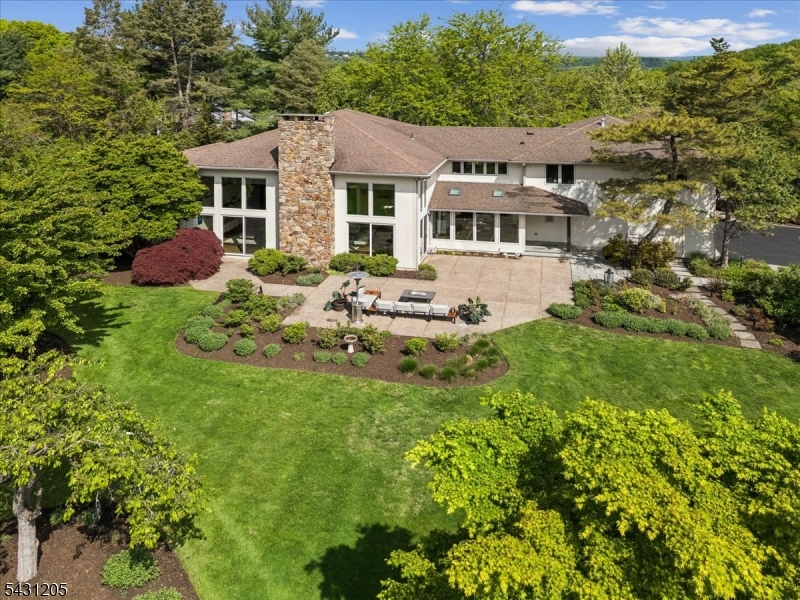 A rare Custom California Contemporary Estate, The Nest offers privacy, scale, and architectural distinction on over 2.5 level acres spanning Morristown and Harding Township. Set in one of Morris Township's most prestigious enclaves and surrounded by luxury estates, this exceptional residence blends clean modern lines, warm natural elements, and a resort-like sense of calm. Dramatic open spaces, walls of glass, rich wood accents, and soaring ceilings over 24 feet create a breathtaking great room anchored by a striking fireplace and designed for entertaining and relaxed everyday living. A thoughtful expansion and renovation enhanced the home's flow while preserving its unique character. The residence features 6 bedrooms, 5 full baths, 2 half baths, a 3-car garage, and a fully finished basement offering flexible space for recreation, fitness, media, work, or guests. A rare main-level primary suite serves as a private retreat with its own entrance, garden access, fireplace, sitting area, and spa-inspired bath. Outdoors, curated grounds with mature plantings, Japanese pines, ornamental maples, open lawns, and garden areas create a serene estate setting with room to further elevate the lifestyle with a pool, tennis court, or enhanced outdoor living spaces. Naturally elevated and thoughtfully oriented, the property captures beautiful light, sunsets, and remarkable privacy, moments from Loantaka Brook Reservation and the restaurants, shops, and conveniences of Morristown.