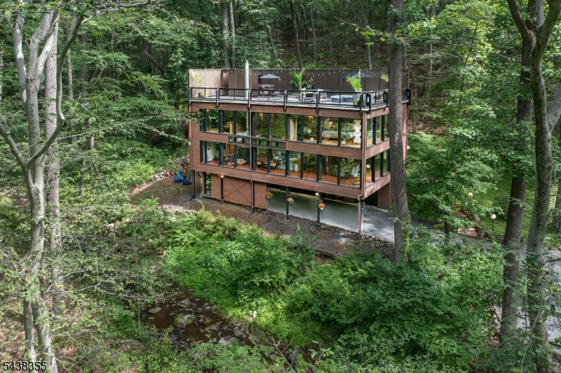 Approximately a one hour drive from NYC leads you to this privately located gem- an exciting and  stunning Custom Contemporary home designed by highly respected NJ architect Michael Zdepski. Originally created as a passive solar house with multiple side windows for cross ventilation, the current owners added efficient mini splits in 2025 for primary heat and ac. Interiors offer spacious rooms with views of the brook and surrounding 3 acre natural landscape. A rooftop deck features a hot tub and offers an ideal spot to relax or entertain. On the main level an open floor plan includes the Living Room with see through fireplace to the Family Room/Breakfast Area, a Dining Area -all generously sized- the Kitchen, Laundry and a full bath. The second floor includes a Primary Bedroom with a fitted walk-in closet and a 2025 renovated bathroom with radiant heat floor. A second bedroom, hall bath, office, den and stairs to the rooftop deck complete this level. Notable features are beamed ceilings, automatic shades for window walls, generator hook up, roof replaced in 2022, EV charger and low maintenance landscaping. 2 bdr septic yet lived as 3 bdr home. Pellet stove, fp and flues sold AS IS with no known issues.Tewksbury Twp is sought after for its scenic roads and natural beauty.  Close to restaurants, golf clubs, equestrian facilities, hiking trails and highways Rte 78 and US 22 are approx 12 mins by car. Please do not enter driveway without a confirmed appointment.Security cameras.