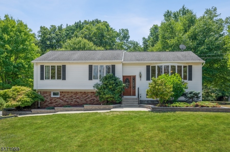 Spacious & secluded on an oversized lot! Move-in ready Bi-Level home 4Bd, 2 1/2Bth & an attached 2-car garage is situated on nearly an acre of manicured property on a quiet cul-de-sac. Offering peaceful privacy in a bucolic setting, this home is close to stores and eateries with quick access to Rt 287, 78 & 22. Beyond the sweeping front lawn, the entryway opens to a sun-filled main level with hardwood floors and great natural light from the huge bow window in the living room and the adjoining dining room. The open flow continues into the light and bright kitchen with granite counters, stainless steel appliances, and warm cabinetry topped with custom crown molding. From the dining room, step outside to a beautiful deck overlooking the expansive back yard with mature shade trees, a patio, a dog run, a large storage shed, and plentiful space for gardening and relaxing. The bedroom wing includes a primary suite with a walk-in closet and full private bathroom, two additional bedrooms, and a full bathroom in the hallway. Additional living space on the ground level includes a large family room with a wood-burning stove and glass sliders to the patio. There also a half bathroom, a fourth bedroom, a workshop, and laundry room. Two stairways from the family room take you to either the front entrance or the kitchen. This spacious, sun-filled home offers comfortable everyday living and entertaining spaces and an exceptional amount of private, beautifully tended outdoor space.