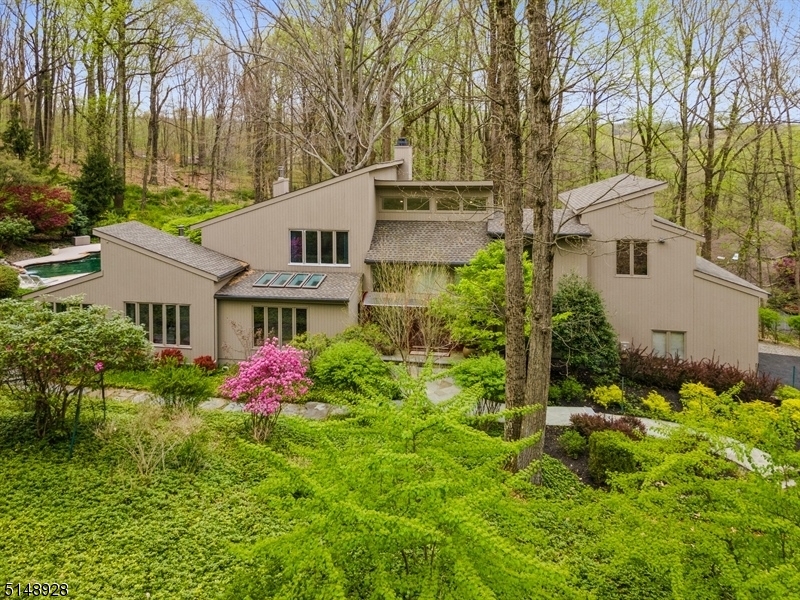 Your private wooded oasis for contemporary living at its best! This striking custom home offers contemporary design w/every modern convenience on 5 acres of exquisitely landscaped wooded acre, a mile down a quiet cul-de-sac. With 4Bd, 4Bths, 2 half Bths & an attached 2-car garage this light-filled residence boasts an astounding vol of space. The interior layout feat soaring ceilings, lrg windows & skylights offering sweeping views over the lushly planted prop & woods. The spacious, open ambience flows from the 2-story foyer & DR to the LR w/a fireplace & a FR where French doors open onto a huge deck feat chef's grill & heated Gunite pool w/a hot tub, waterfall, & free-form design blending perfectly into the landscape. A sleek & stunning kitch w/high-end appls, granite tops & skylights that drench the space in sunlight. The luxurious 1st Fl Primary BD suite feat a vaulted ceiling, sitting area w/a fireplace, WIC & a palatial en suite BTH w/dual vanities, jetted tub & steam shower. The 2nd fl incl 2Bd, one w/a huge WIC & en suite Bth, convenient laundry rm, hallway Bth & a sunny library w/built-in shelving.  The finished basement w/private entrance offers more luxurious & highly flexible space. The Rec-room is perfect for movies, gaming, workouts, or cozy conversation, while the kitchenette & large guest rm w/full en suite Bth will complete a guest/in-law or home office/consulting suite. Another 1/2 Bth & hundreds of sqf of secure, wide-open storage space complete the level.