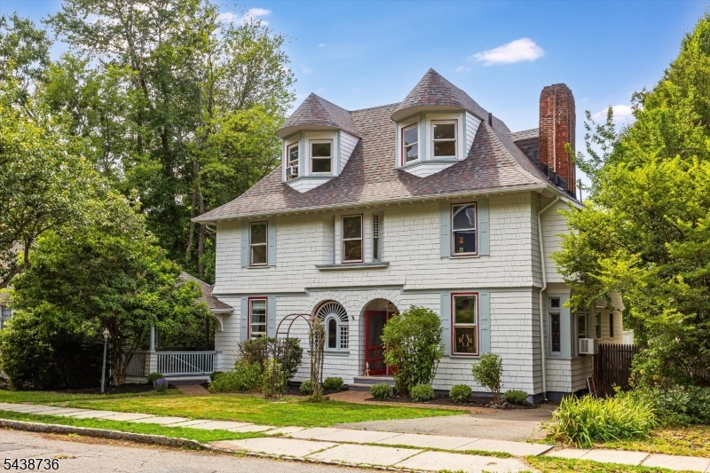 This postcard-worthy 1890 Victorian sits on nearly a half acre in the heart of West Montrose, close to Meadowland Park, bustling downtown, and two train stations with direct service to Penn Station. With five bedrooms, two-and-a-half baths, and ornate details throughout, the home offers timeless elegance while still feeling warm, welcoming, and compatible with modern-day living. Alcoves, nooks, and built-in benches appear throughout the home, creating inviting spots to read, nap, or just daydream. The newly updated kitchen features new cabinets, counters, and tile, plus a pantry and plenty of room to cook while guests sit, snack, and sip at the center island. Just beyond, a spacious den opens to a stunning wraparound porch overlooking the nearly half-acre lot. In the living room, warm up by the fireplace, watch the game, or settle in for movie night. Glass sliders frame views of the yard, where bunnies, deer, and other wildlife often pass through. The dining room adds another fireplace, a beautiful built-in hutch, and a wall of stained-glass windows. A half bath completes the main level. Up the grand staircase, the second floor offers three bedrooms and a beautifully appointed hall bath. A fourth bedroom opens to a deck overlooking the yard. The third floor includes an additional bedroom and full bath, creating a flexible space for a primary suite, guest suite, or private work-from-home space.