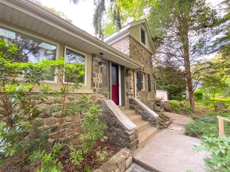Find your Zen in this distinctive 3-bedroom, 2-bath custom stone home in Denville's sought-after Rock Ridge community. Set against the peaceful backdrop of Jonathan's Woods parkland, this one-of-a-kind property blends natural stonework, exposed beams, vaulted ceilings, skylights, and a dramatic wood-burning fireplace into a setting that feels more like a private retreat than a typical suburban home.An expansive solarium overlooks the private wooded backyard, creating a light-filled space to relax, entertain, or simply enjoy the changing seasons. Recent improvements include a new roof, rebuilt chimney, and professionally installed backyard paver patio.Rock Ridge Lake is directly across the street, offering opportunities for kayaking, canoeing, fishing, and year-round enjoyment of the natural surroundings. Optional Rock Ridge Club membership provides additional recreational and social opportunities.A detached heated studio with powder room offers exceptional flexibility for a home office, fitness studio, creative retreat, music room, workshop, hobby space, or private getaway. Enjoy exceptional privacy just minutes from vibrant downtown Denville, shopping, dining, major highways, and NJ Transit. A truly unique property combining architectural character, versatile bonus space, and an outstanding Rock Ridge location.