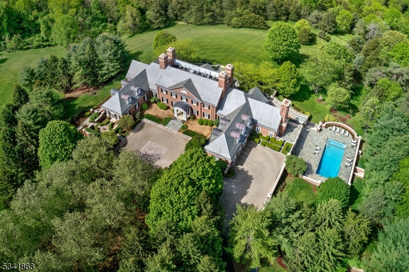 PRICE IMPROVEMENT! Privately secluded on 32+ acres overlooking westerly hillsides, this distinguished estate is unique in its capability to protect and endure. Reminiscent of a turn-of-the-century all-brick Georgian Mansion with a true slate roof, the estate's location atop the Bernardsville Mountain is wrapped by breath-taking grounds and captivating views.  A handsomely gated entry is augmented by multiple security systems, while its concrete and steel beam construction brings walls to almost 2-ft thick.  Meticulous detail and unparalleled craftsmanship created finely appointed rooms of both grand and intimate proportions accented by antique architectural elements; exquisite wood floors; 10' ceilings defined by hand-milled moldings; and a masterfully crafted 2-story library with softly lighted dome. A sprawling walk-out recreation level includes a spa, sauna, card room, billiard room, media/family room and access to the pool. For those who work from home: a multi-room office suite on this level includes a separate entry and kitchenette. For serious wine collectors: a brick groin-vaulted wine cellar for 16,355+ bottles and an elegant tasting room.  A separate 4-bedroom cottage is ideal for staff or guests.  A silent underground generator runs the entire property.  One of the most important estates in New Jersey is less than an hour's drive to New York. Sq.Ft. estimate is per architect plans for all three levels.