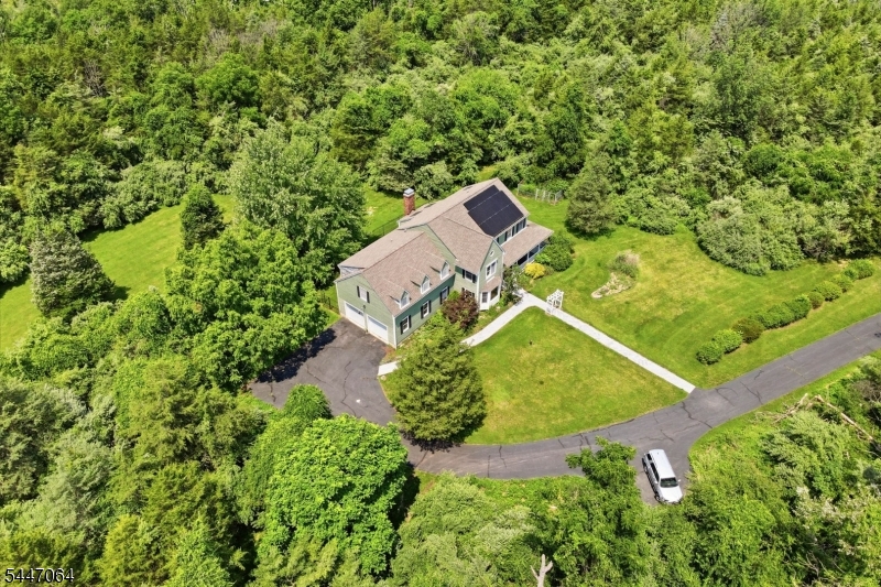 Tucked away at the end of a long private driveway on 15 picturesque acres in Fredon Twp., this custom Colonial offers privacy, space, and endless potential. A newer paver walkway leads to the inviting wraparound front porch. Inside, hardwood floors flow throughout the main level, featuring a spacious floor plan ideal for everyday living and entertaining. The oversized kitchen opens to a sun filled breakfast area with an impressive arched window, skylight, and access to the rear trex deck overlooking the peaceful property. A formal dining room, formal living room, and oversized family room with a wood burning fireplace and two skylights provide plenty of gathering space. Just off the family room, the solarium style sunroom features cedar ceilings, a utility sink, and backyard access, making it perfect for plants or potting. A first floor office or den with French doors, spacious laundry room with exterior access and two pantry closets, powder room, and attached two car garage complete the first floor. Upstairs offers a generous primary suite with double vanity, jetted tub, and separate shower, plus four additional bedrooms and two full baths. A full unfinished basement provides excellent storage or future living space. Additional highlights include a 5-year-old roof, new Roth oil tanks, solar panels, and a passing septic inspection on file. Bring your vision and make this exceptional property your dream home.