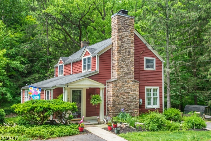 A storybook setting for this enchanting 3-bedroom home boasting 3 levels of living space nestled on a tree-lined lot with stream in the historic Stephensburg section of Washington Twp.  A covered front porch leads you into a charming sitting room-office overlooking the living room with impressive, floor to ceiling, raised hearth wood burning fireplace with stone surround and built-in bookcases on either side. The dining room with wainscoting has sliding doors that open onto an expansive deck to enjoy your morning coffee to the soothing sounds of Stephensburg Creek. The updated eat in kitchen features granite counters, subway tile backsplash, stainless appliances, recessed lights & pantry. Wood floors in all the bedrooms (under carpet in the primary BR). Updated full bathroom with granite topped vanity, linen closet and tub/shower. The walk-out basement offers additional living space with carpeted floor, pellet stove, unique stone bay windows, built-in window seat, half bath, laundry area, and utility/storage closets. Fabulous nearly 2-acre property with stream, stone walls, and flower beds. Just enough privacy between neighbors and front & back view to woods. Automatic propane generator for peace of mind. Top-rated West Morris Schools. Minutes to Mansfield shopping: Walmart, Kohls, Shoprite, theater, local farms, craft breweries and restaurants. Ready for new owners to bring their loving touch and continue the history of this appealing home and property.