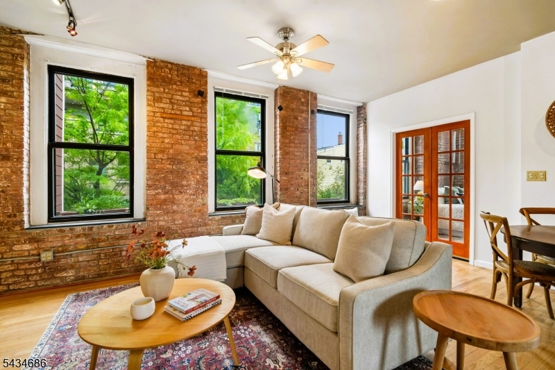 Discover authentic loft living at the iconic Chocolate Factory Lofts in Newark's vibrant Ironbound district, just two blocks from Newark Penn Station with direct access to NYC. This distinctive residence blends historic character with modern comfort, featuring soaring ceilings, exposed brick walls, heavy timber columns, oversized windows, central air conditioning, and an open-concept layout filled with natural light. Thoughtful architectural details throughout include antique raised panel doors, pocket doors, salvaged wood kitchen shelves, custom handmade tile, granite counters, and hardwood flooring that complement the loft's industrial character. Enjoy peaceful garden views and exceptional cross ventilation from North, East, and South exposures, a rare feature that enhances both light and airflow throughout the home. The spacious living and dining areas create an ideal setting for entertaining, relaxing, or working from home. The loft offers two sizable bedrooms and a rare garage parking space for added convenience. Located in one of Newark's most dynamic neighborhoods, enjoy easy access to restaurants, cafes, shopping, NJ Transit, PATH trains, Newark Liberty International Airport, Prudential Center, and all that Downtown Newark has to offer.