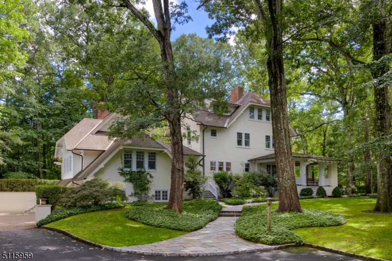 One of Summit's most incredible North Side properties perched on a secluded and private property of nearly 2 acres! Minutes to downtown Summit and NYC train, this 1907 home is an extraordinary architectural masterpiece complete with masterfully executed renovations and additions including remodeled kitchen with Rutt cabinetry & updated baths. New mahogany porches, perennial gardens, walking paths, and ample outdoor space for entertaining! Grand Entry foyer with original stained-glass windows and stately original wrap-around staircase. Magnificent reno'd gourmet chef's kitchen with butler's pantry. Oversized family room addition with 16' ceilings and adjacent deck w/ pergola. Regal dining room with fireplace and sophisticated details. Elegant living room and music rooms. Delightful atrium and first-level home office. Primary suite with spa-like bath, dressing room w/ custom built-ins and walk-in closet. Full Baths brand NEW with completely on-trend designer tile, vanities, and LED mirrors. Second and third-level bedrooms with plenty of light and storage. Amazing Lower Level with Recreation/Billiards Room, Gym, Wine Cellar, Work Room, Laundry Room, Mud Room off 4-Car attached Garage and SO MUCH storage. A home of this caliber, completely encased in nature, is an exceedingly special opportunity for buyers seeking estate-like property, tremendous luxury, and immense privacy.